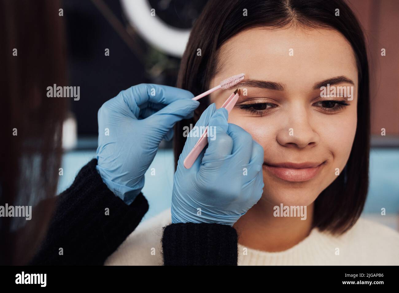 Close Up Female Master Combs the Eyebrow to Young Woman, Process of