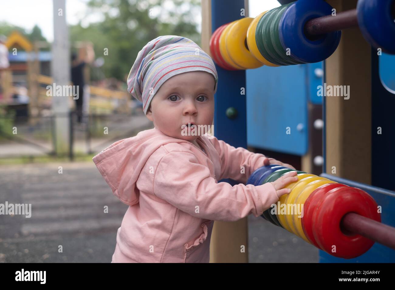 Caucasian baby girl playing with colored rings on playground. Stock Photo