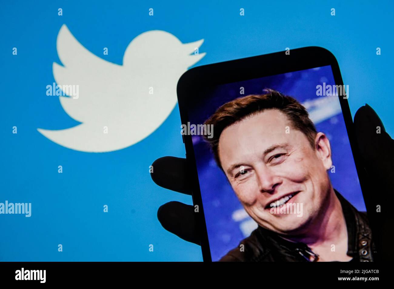 Guwahati, India. 09th July, 2022. In this photo illustration, Twitter logo is displayed on a laptop screen as person looking an image of Elon Musk on a smartphone. Elon Musk terminated the purchasing agreement of the social media company Twitter for approximately $44 billion. Credit: David Talukdar/Alamy Live News Stock Photo
