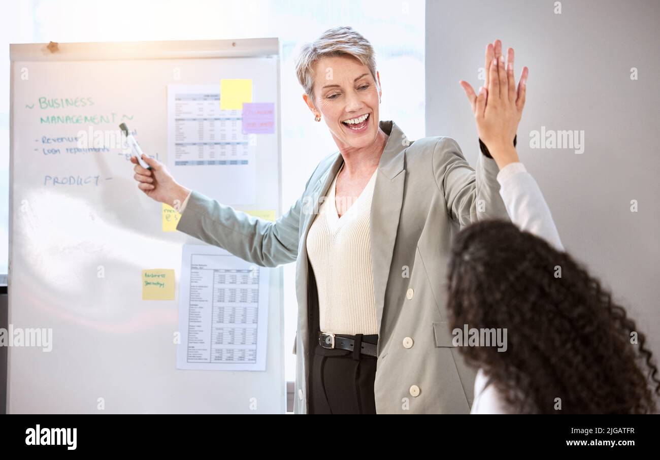 Chasing after success with every plan they make. a senior businesswoman giving her colleague a high five during a meeting in an office. Stock Photo