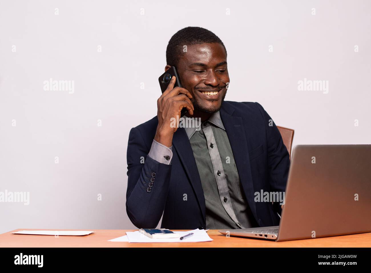 black businessman making a call while using his laptop Stock Photo