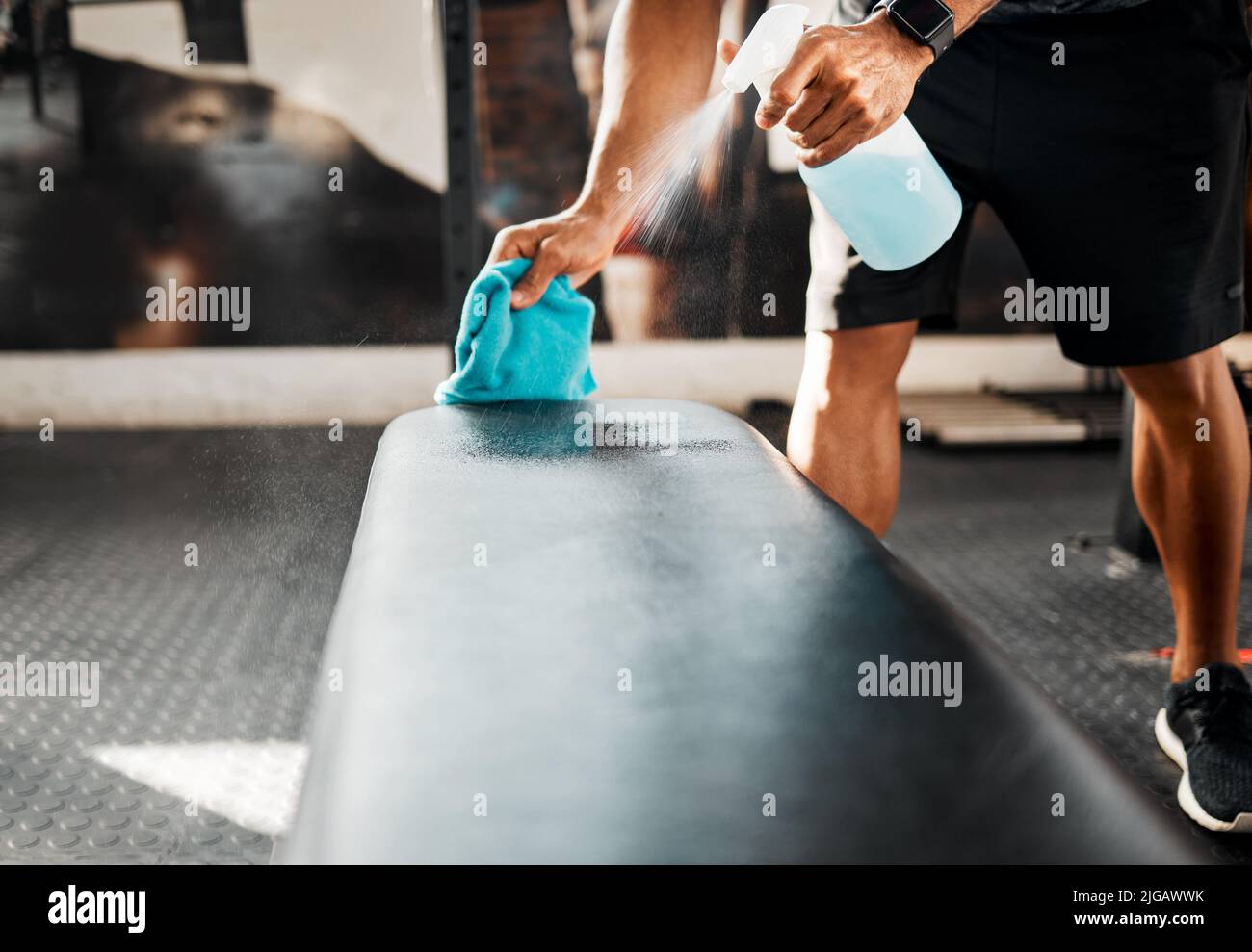 Bacteria can spread so easily. a business owner sanitizing the work benches in their gym. Stock Photo