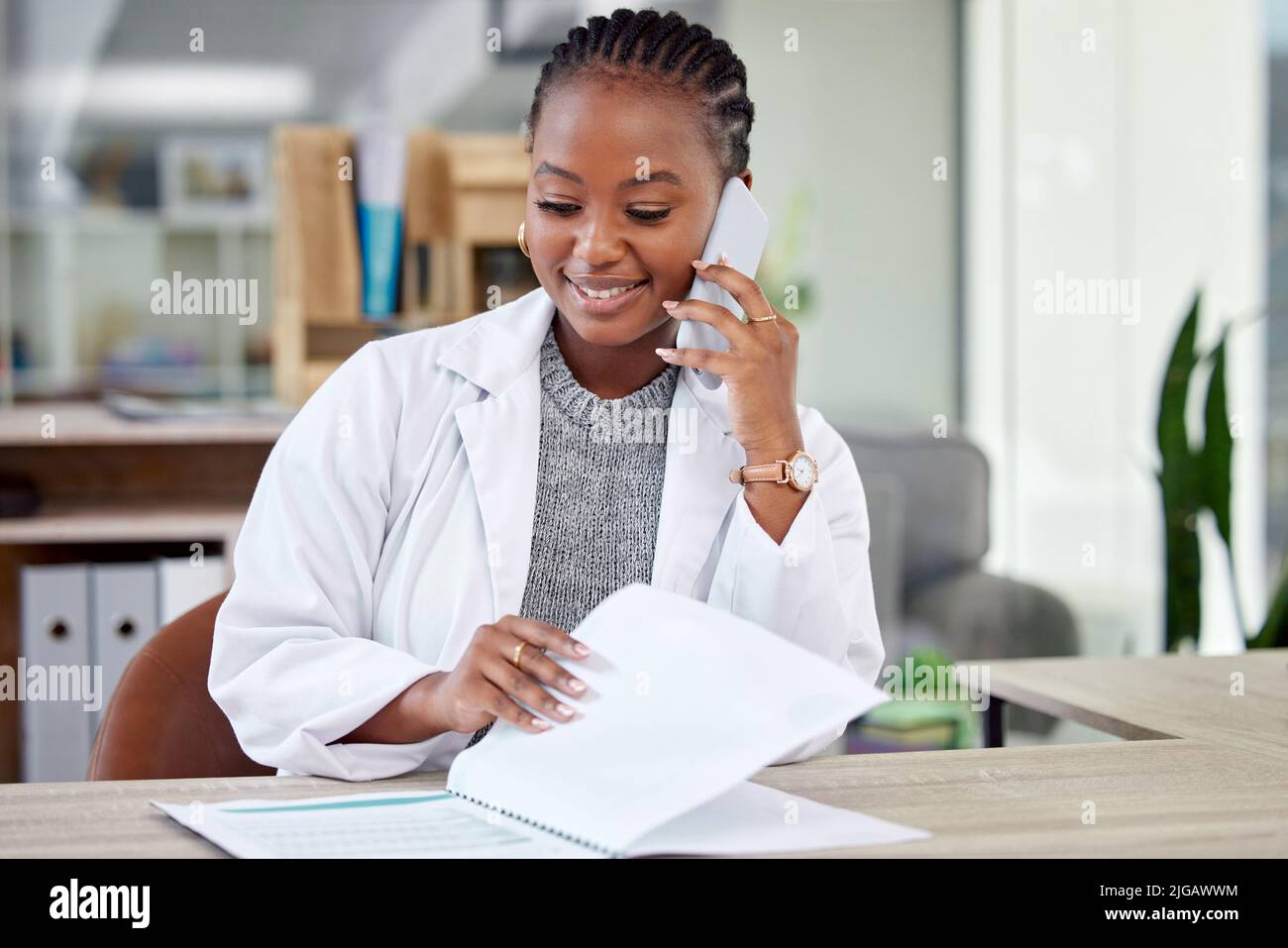 Technology has greatly helped modern medicine. a young female doctor making a phone call using her smartphone. Stock Photo