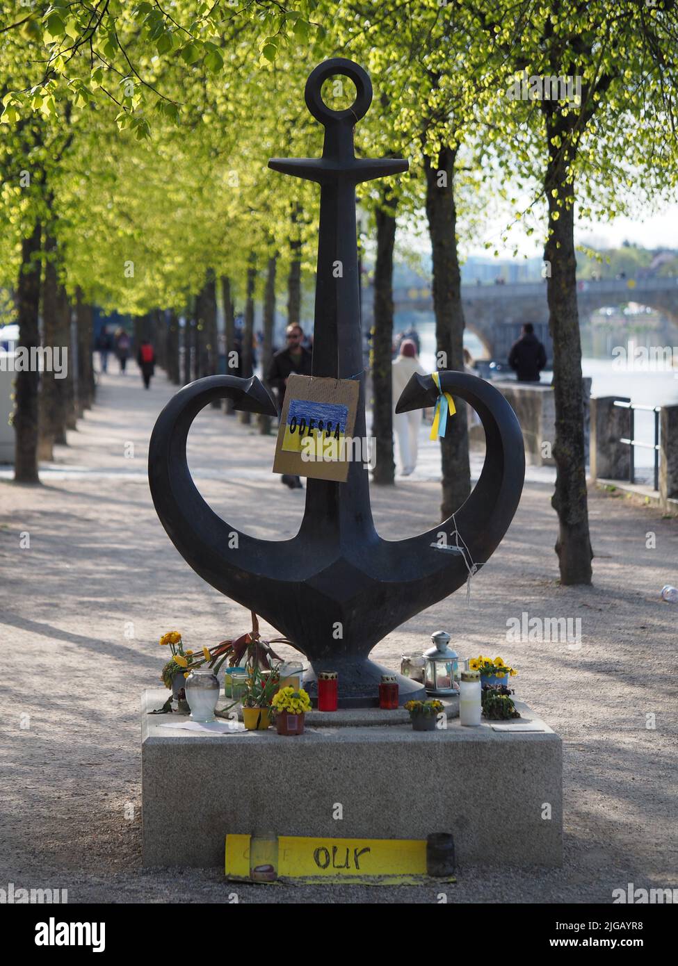 A vertical shot of an anchor statue in Ratisbona stocked with a small Ukrainian flag placed in a park Stock Photo