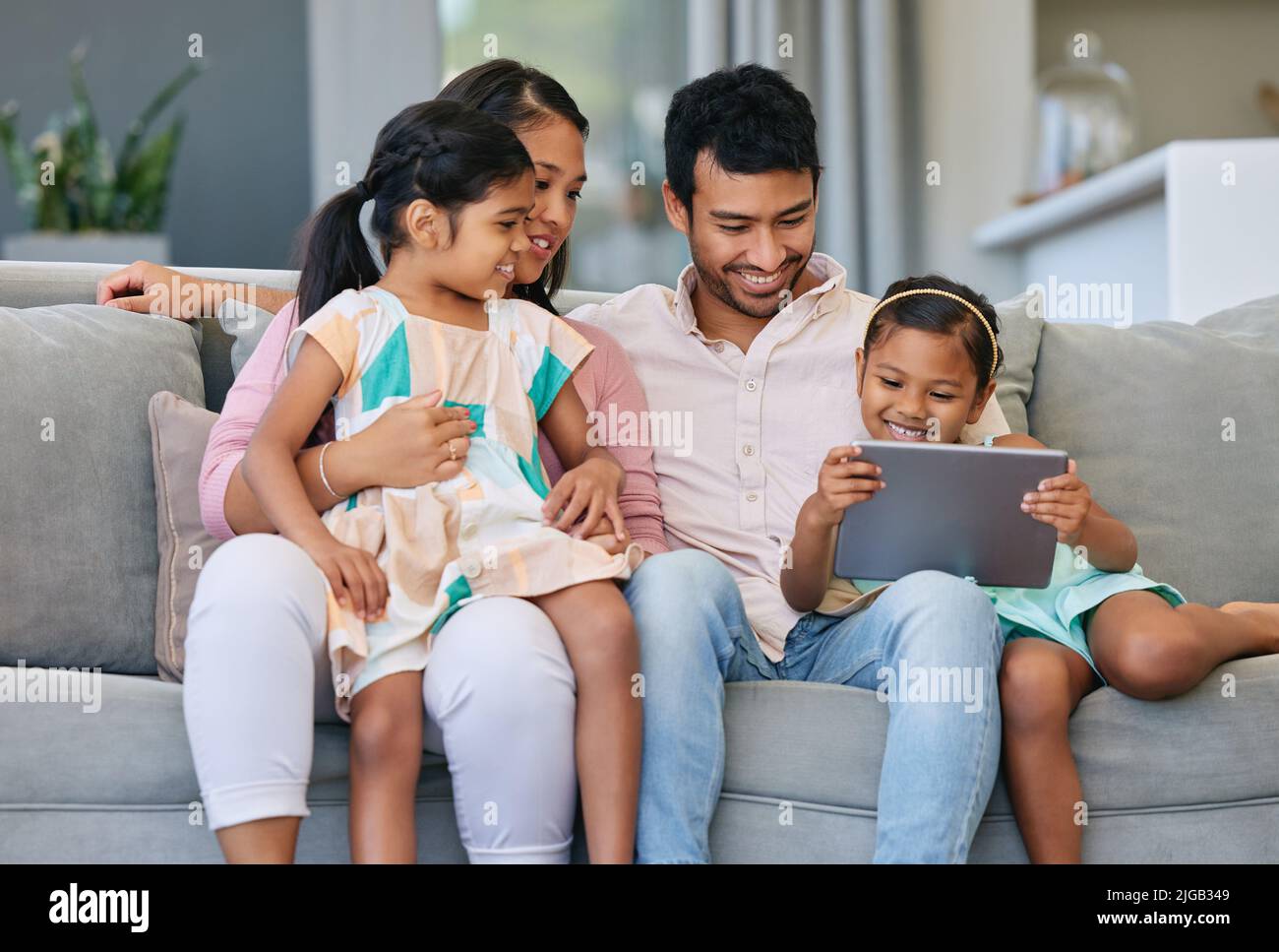 Technology can bring families together. a young family relaxing together while using a digital tablet. Stock Photo