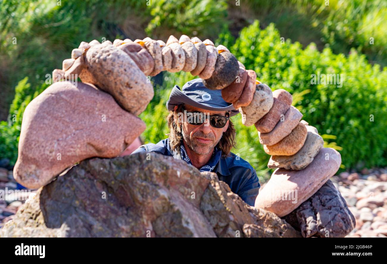 Dunbar, Scotland, UK. 9 July 2022. Day one of the 11th Stone Stacking Championships held at Eye Cave Beach in Dunbar in East Lothian. . Competitors are shown during the arch building competition. Pic; Pedro Duran and his stone arch. Iain Masterton/Alamy Live News Stock Photo