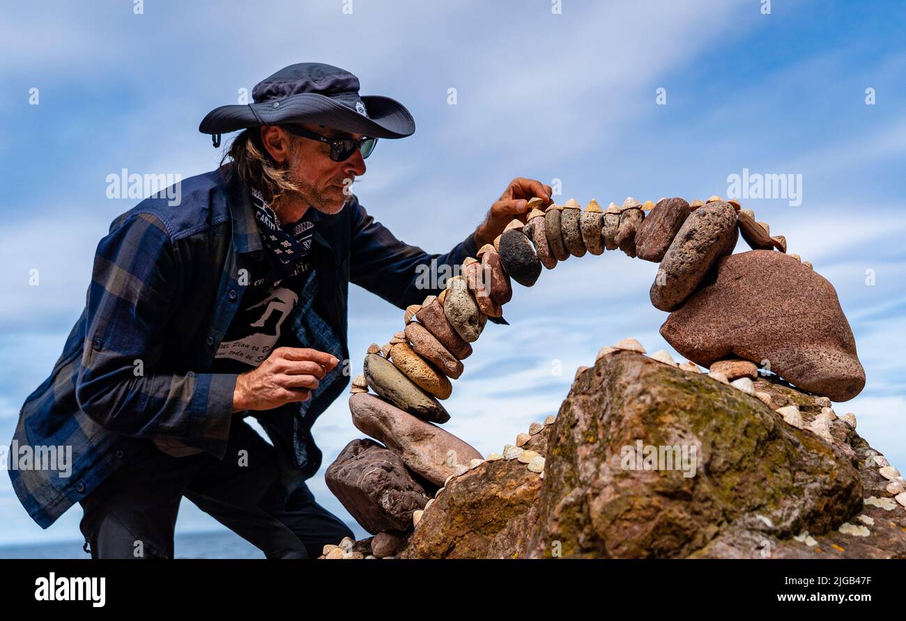 Dunbar, Scotland, UK. 9 July 2022. Day one of the 11th Stone Stacking Championships held at Eye Cave Beach in Dunbar in East Lothian. . Competitors are shown during the arch building competition. Pic; Pedro Duran and his stone arch. Iain Masterton/Alamy Live News Stock Photo