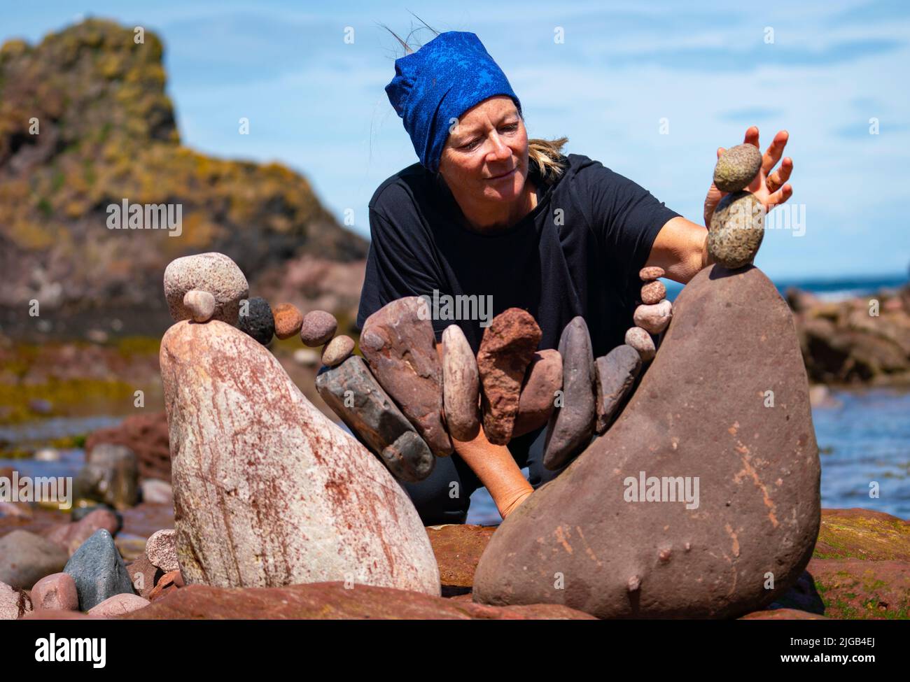 Dunbar, Scotland, UK. 9 July 2022. Day one of the 11th Stone Stacking Championships held at Eye Cave Beach in Dunbar in East Lothian. . Competitors are shown during the arch building competition. Pic; Caroline Walker buds a stone arch.  Iain Masterton/Alamy Live News Stock Photo