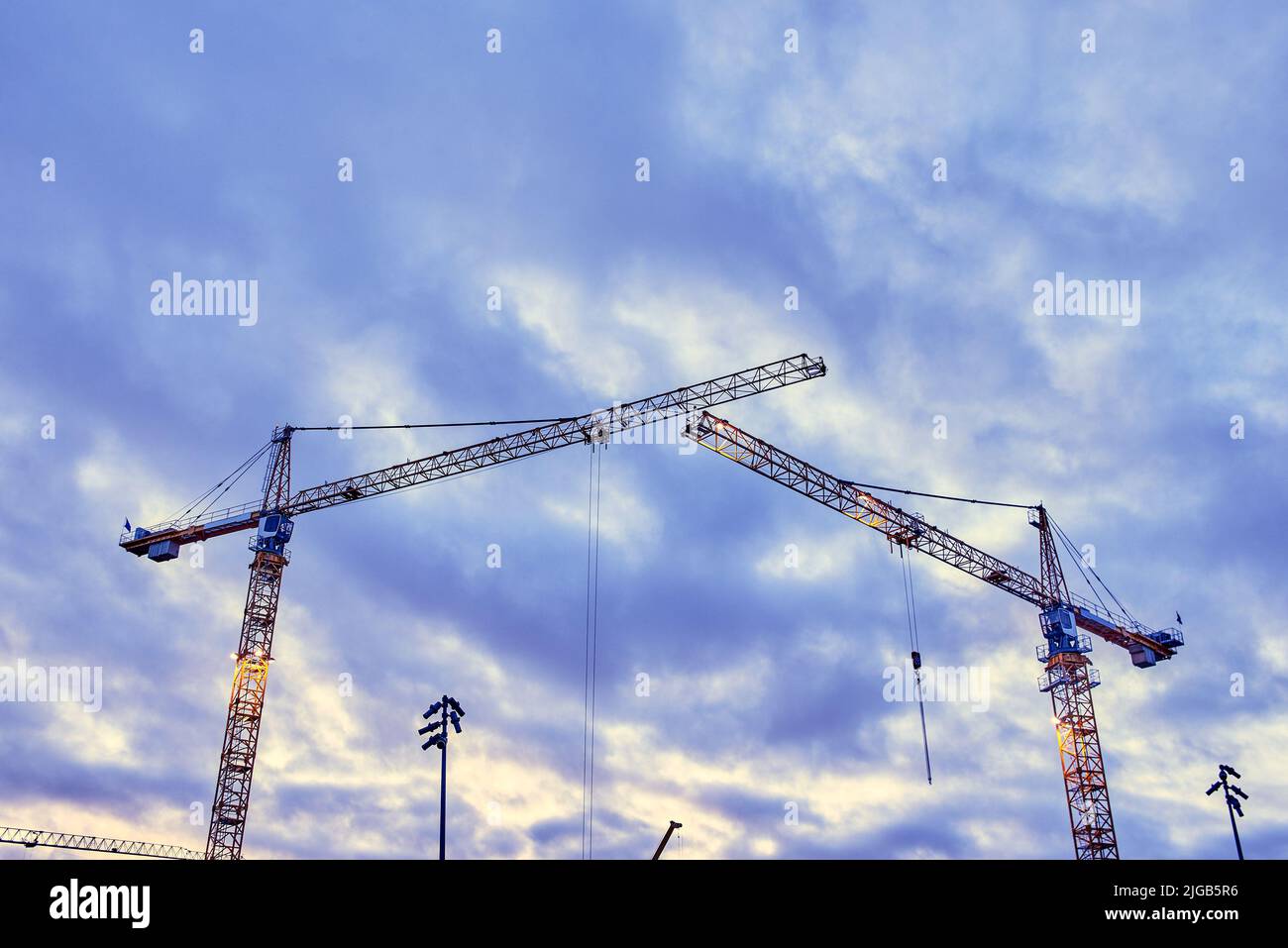Construction cranes against the dark sky background Stock Photo - Alamy