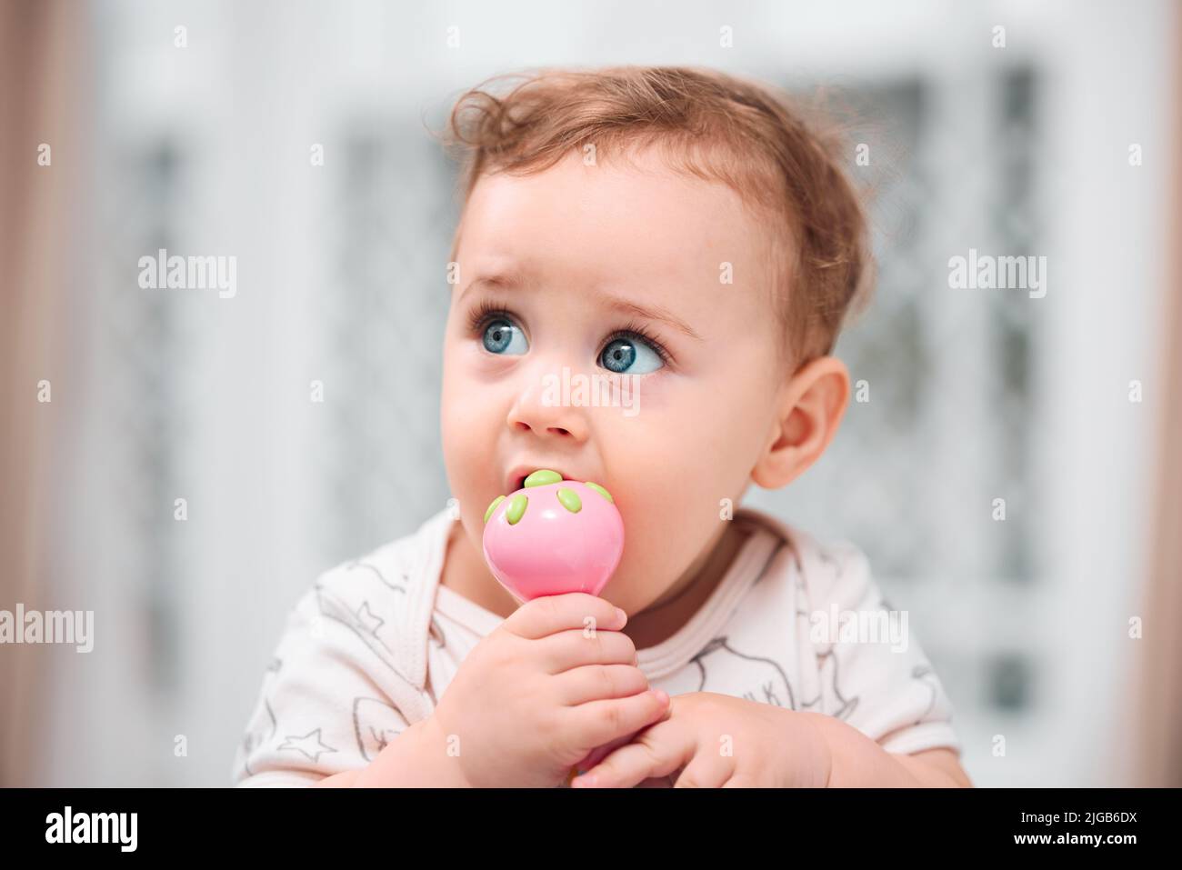 Someone is teething. a little baby boy biting on a top. Stock Photo