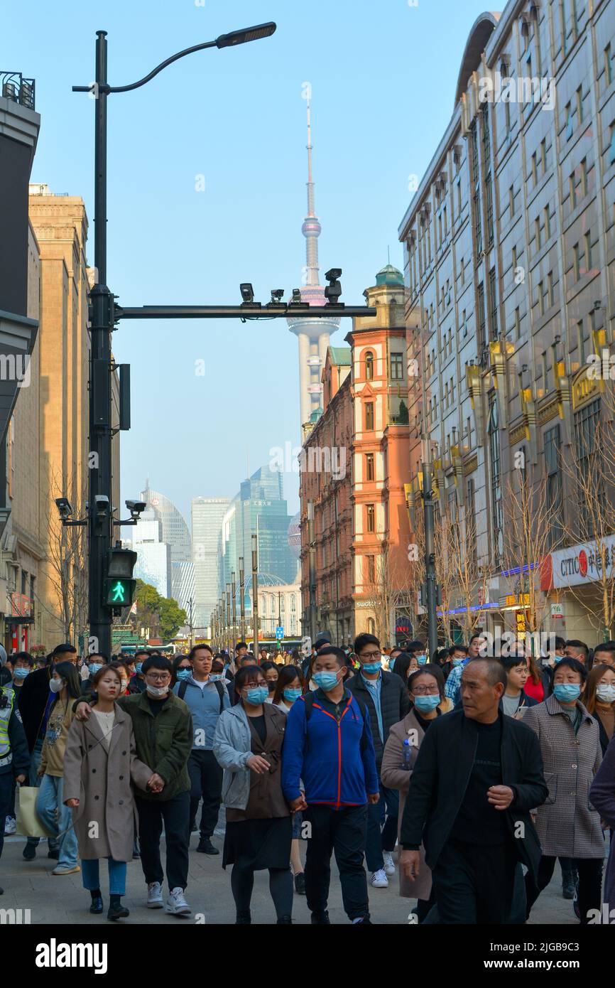 People walking in a street in Shanghai, China under the street lamp with arrays of multiple security cameras. The bund and Oriental pearl tower behind Stock Photo