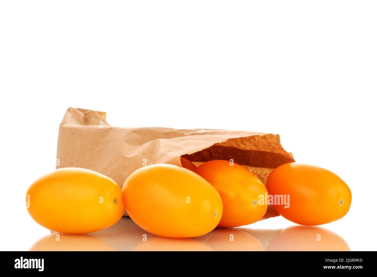 Several ripe yellow tomatoes with a paper bag, close-up, isolated on a white background. Stock Photo