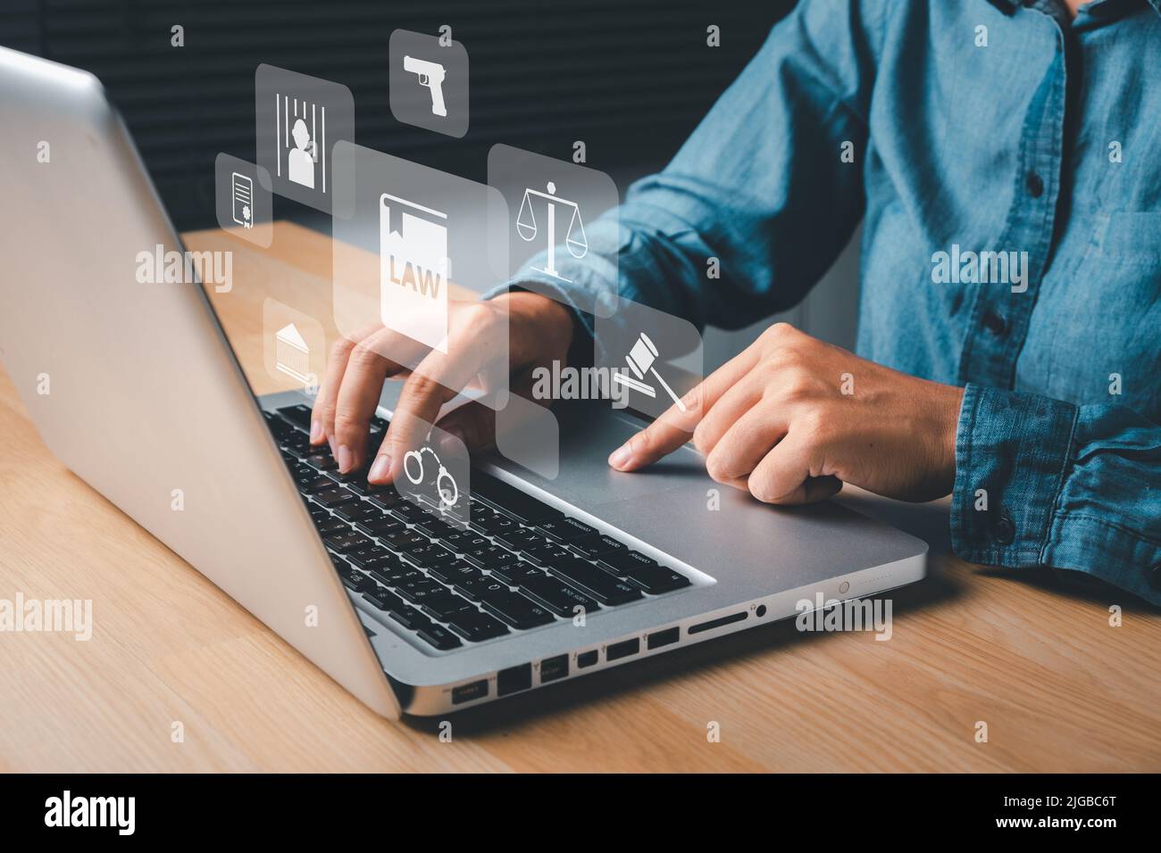 Female lawyer hand using laptop computer with holographic law icon on office desk, terrorism, crime, judgment, verdict, justice and law concept. Stock Photo