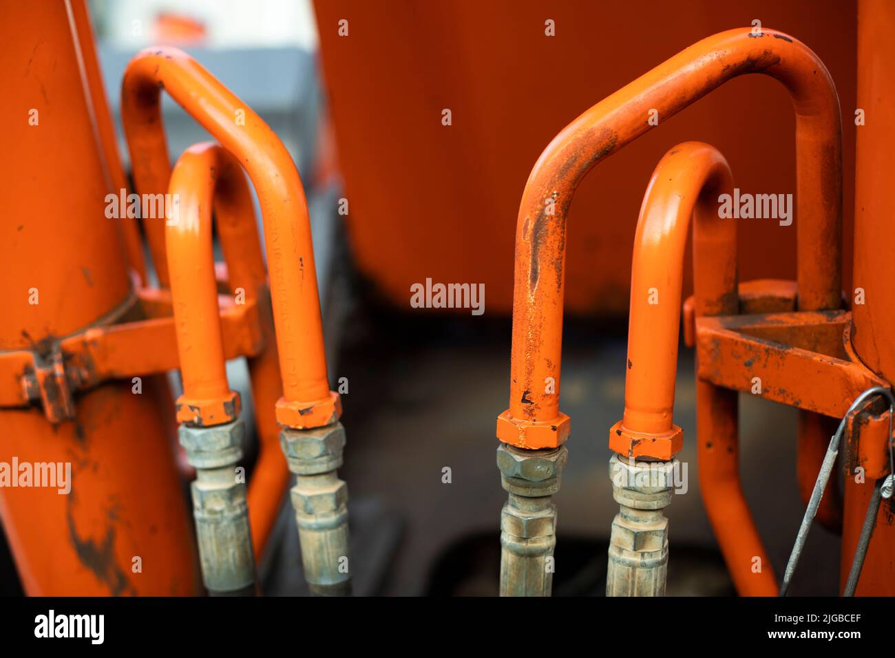 Steel fuel pipes. Tractor parts. Heavy machinery up close. Orange