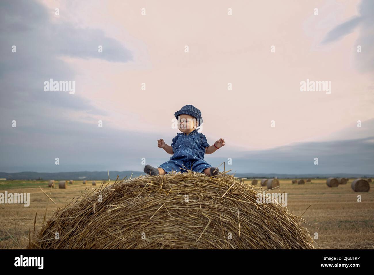 child in a wheat field.smiling cute girl on a gold wheat field at sunset. Stock Photo
