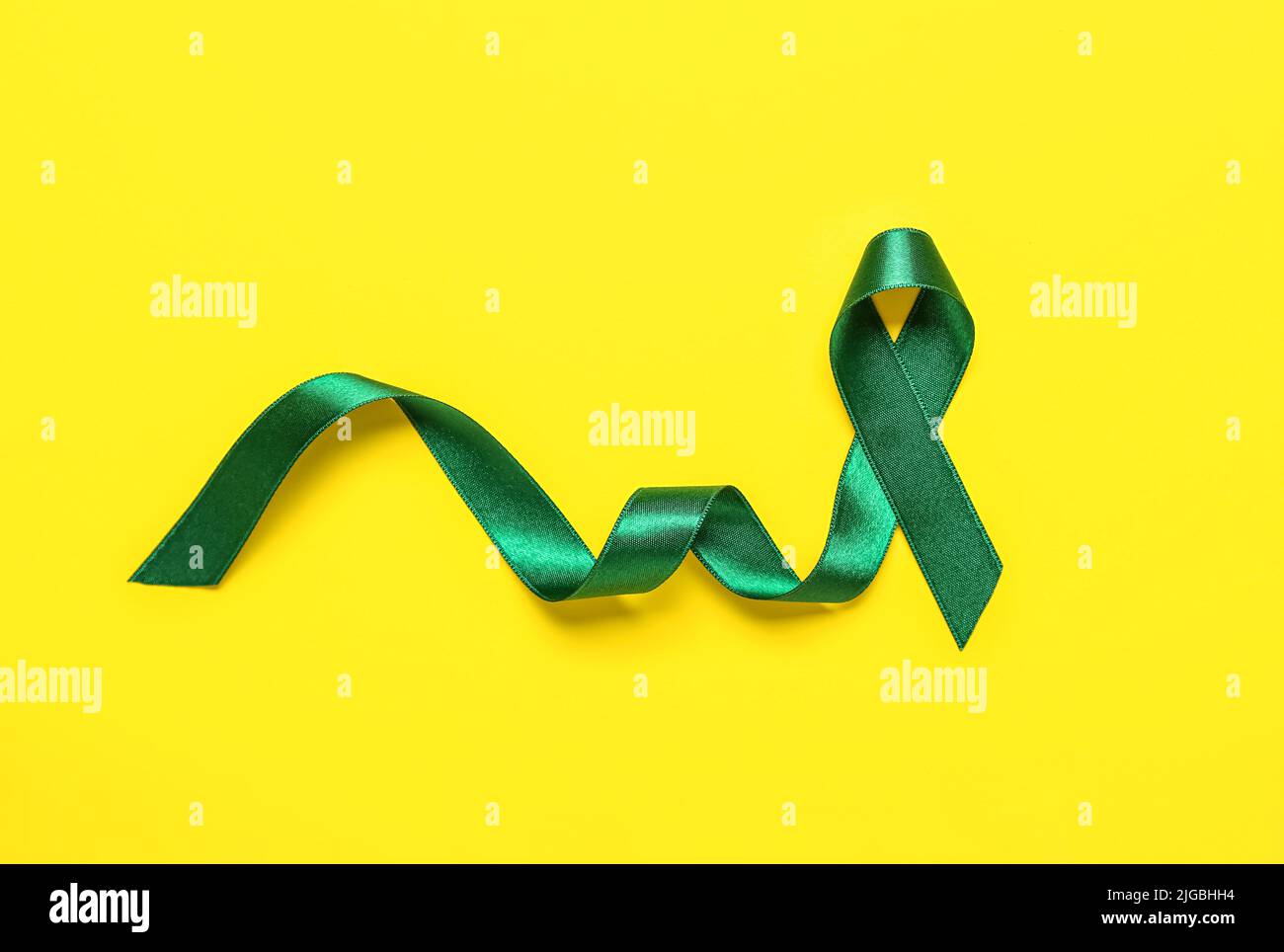 Green ribbon on yellow background. Liver cancer concept Stock Photo Alamy