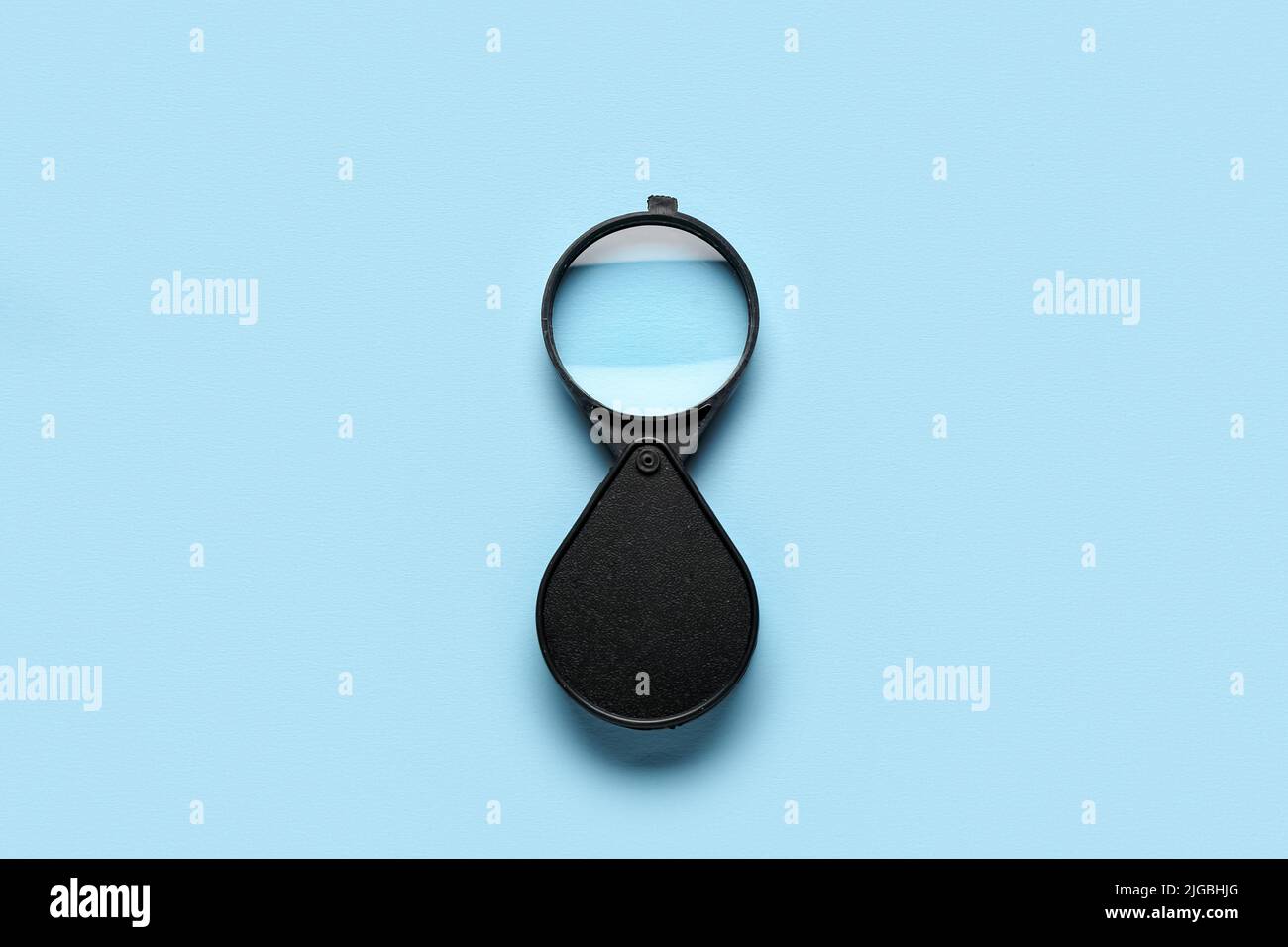 Magnifying glass on light blue background Stock Photo - Alamy