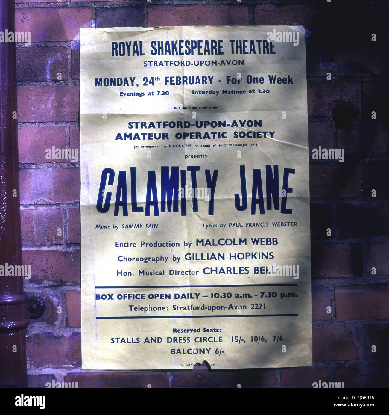 1969, on external brickwall, a poster advertising a Stratford -Upon-Avon Amateur Operatic Society production of 'Calamity Jane' at the Royal Shakespeare Theatre, Stratford-Upon, England, UK. Calamity Jane was a musical western stage play based on the successful 1953 film featuring Doris Day and Howard Keel, telling the adventures of a bawdy American heroine. Founded in 1921, the Stratford-upon-Avon Amateur Operatic Society's first production was The Mikado at the Old Shakespeare Memorial Theatre in 1922. The society was renamed as the Stratford Musical Theatre Company in 2010 Stock Photo