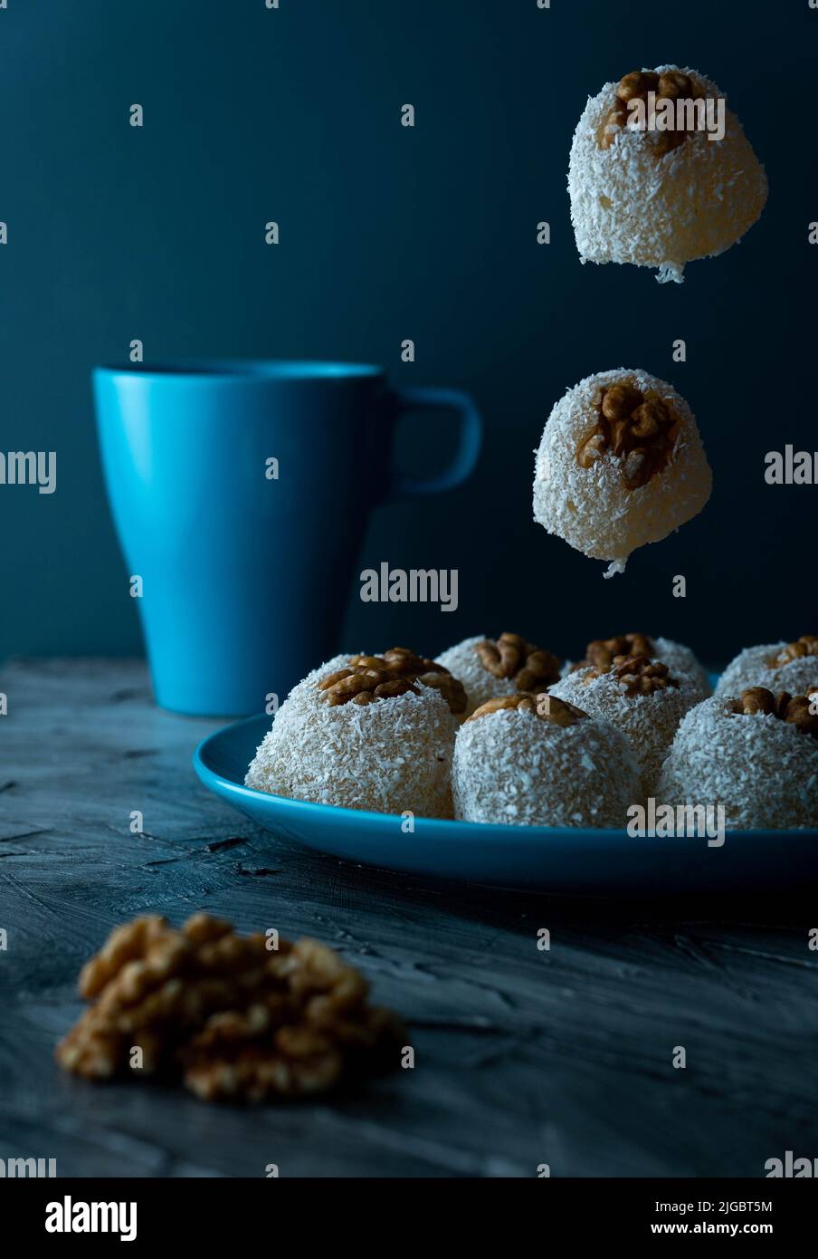 A vertical closeup of walnut sweets with green tea in a blue setup ...
