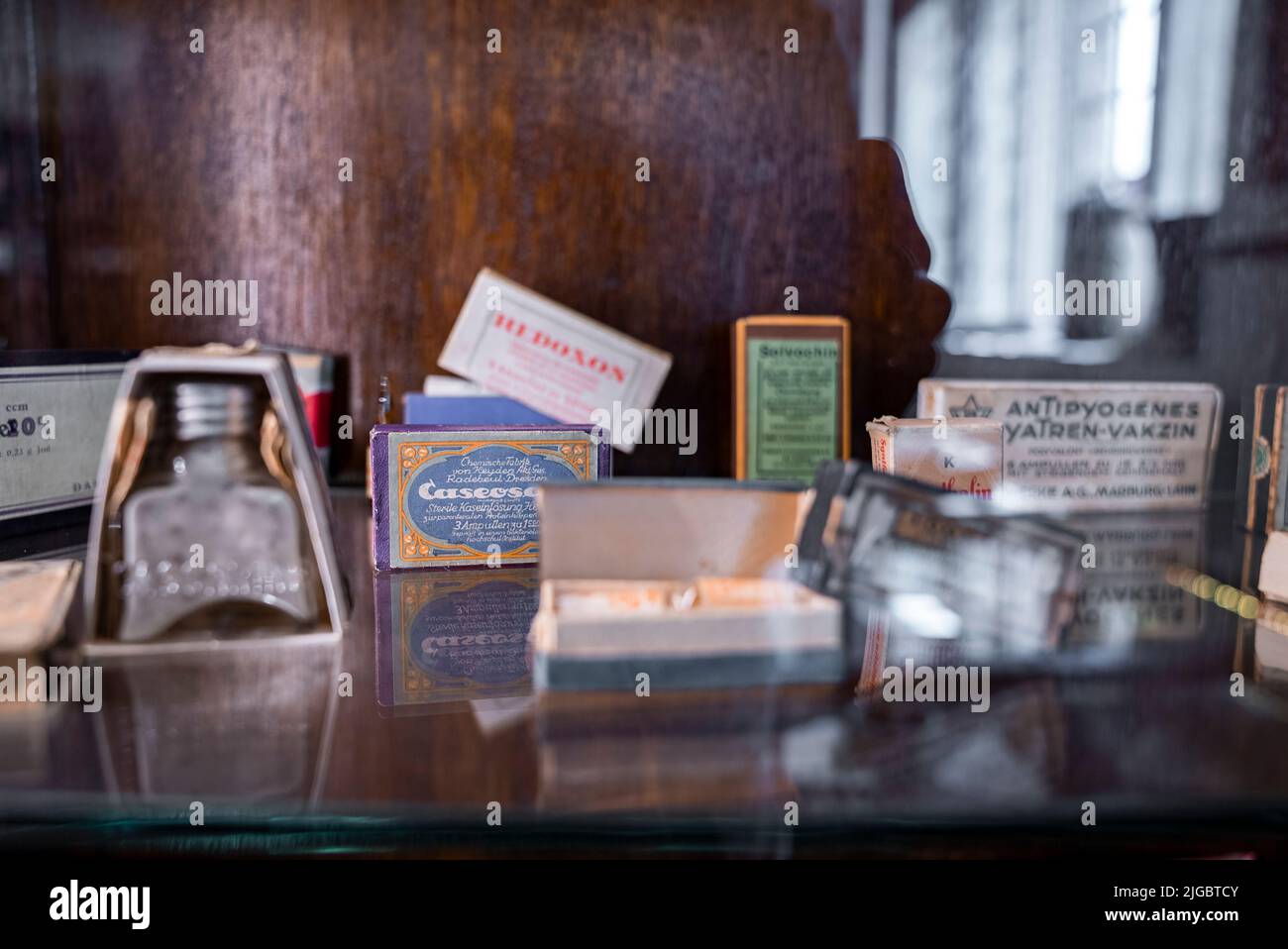 Various objects in boxes on glass shelf at old pharmacy museum in historic town Stock Photo