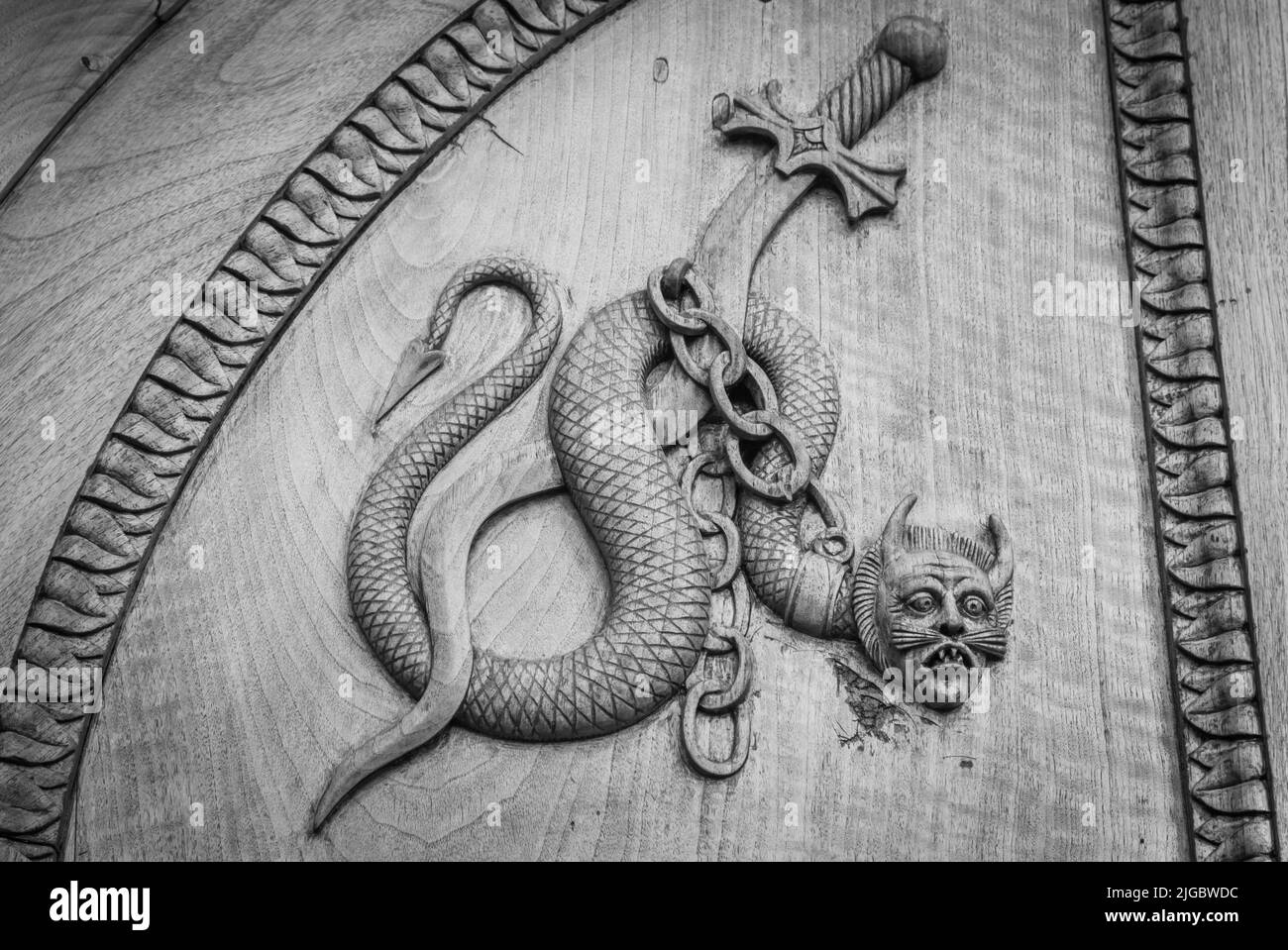 Devil snake symbol. Fantasy magic creature on an old door, 12th Century Abbey, Italy. Stock Photo
