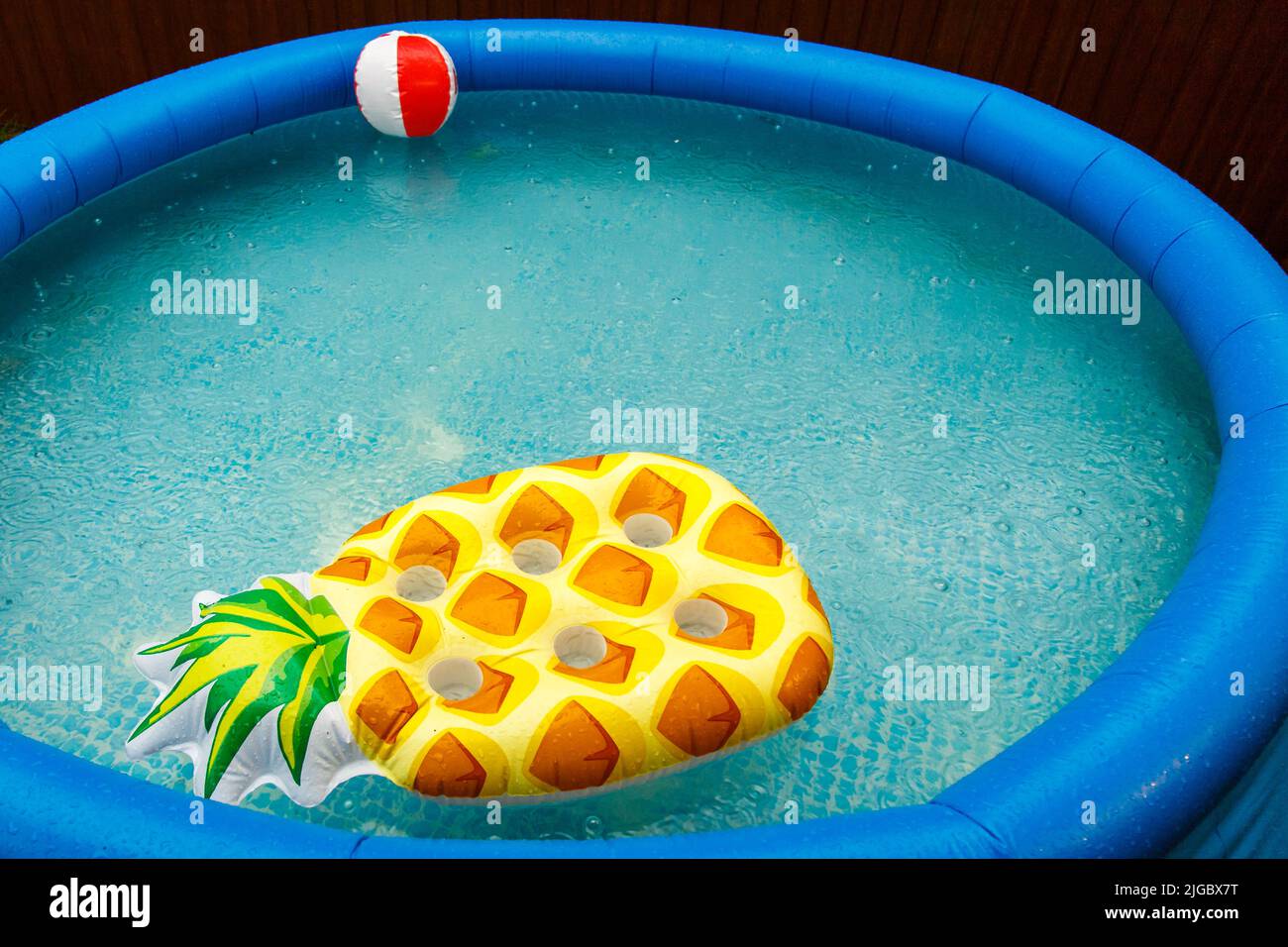 Float mattresses in the pool, it's raining. Blue inflatable pool An