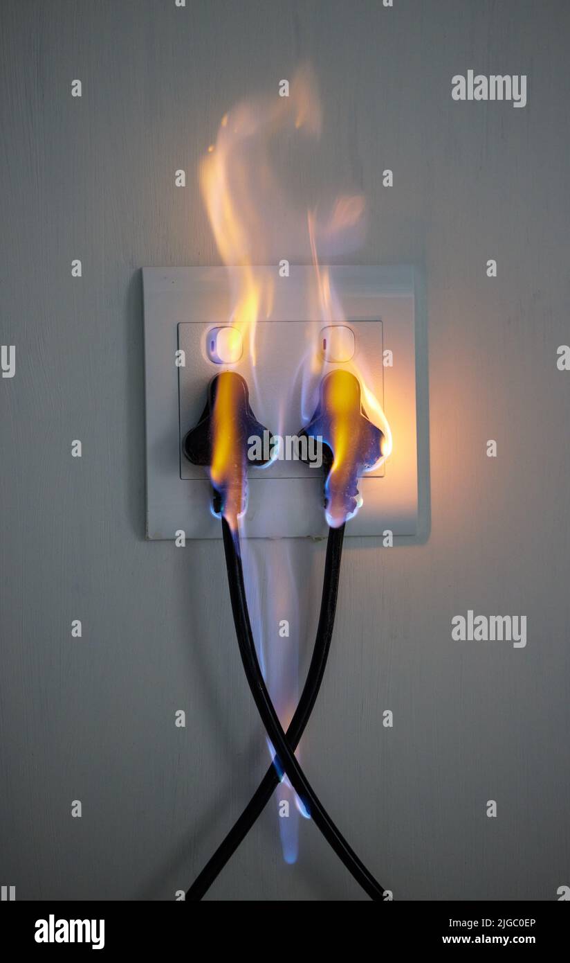 It can happen to anyone. two plugs in a wall socket catching fire Stock Photo Alamy
