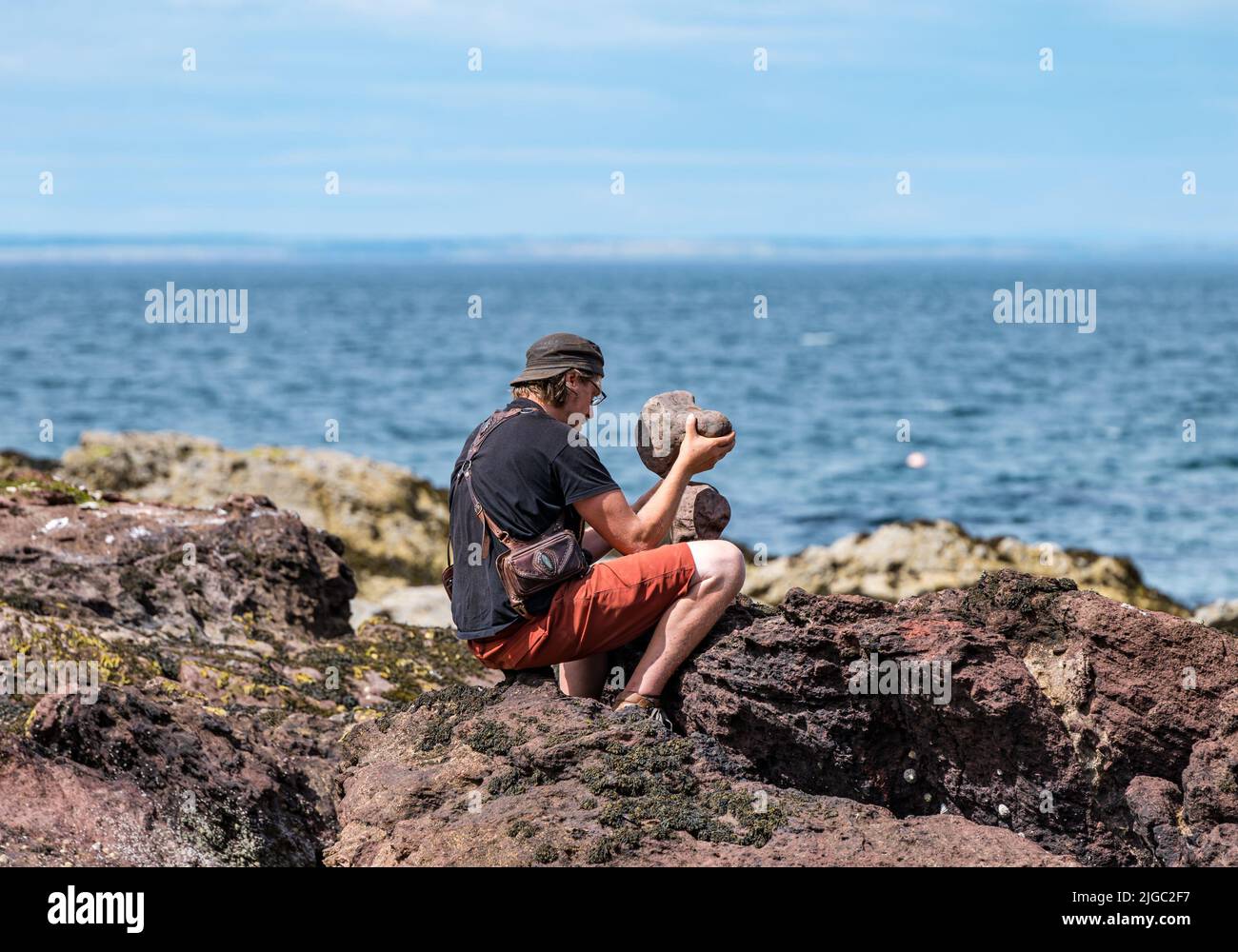 Dunbar, East Lothian, Scotland, UK, 9th July 2022. European Stone Stacking Championship: participants have 3.5 hours to create an artistic artwork from the rocks on Eye Cave Beach. Pictured: Michael Grab, stone stacker Stock Photo