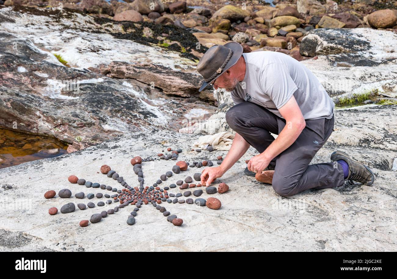 Dunbar, East Lothian, Scotland, UK, 9th July 2022. European Stone Stacking Championship: participants have 3.5 hours to create an artistic artwork from the rocks on Eye Cave Beach. Pictured: Laurence Winram, land artist Stock Photo