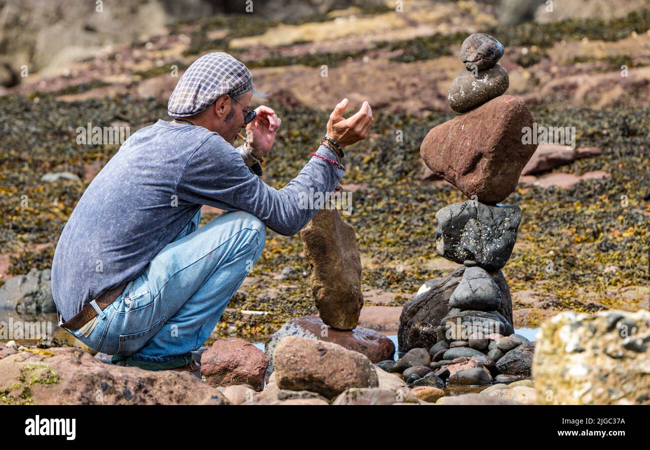 Dunbar, East Lothian, Scotland, UK, 9th July 2022. European Stone Stacking Championship: participants have 3.5 hours to create an artistic artwork from the rocks on Eye Cave Beach. Pictured: Charlie Jordan, stone stacker Stock Photo