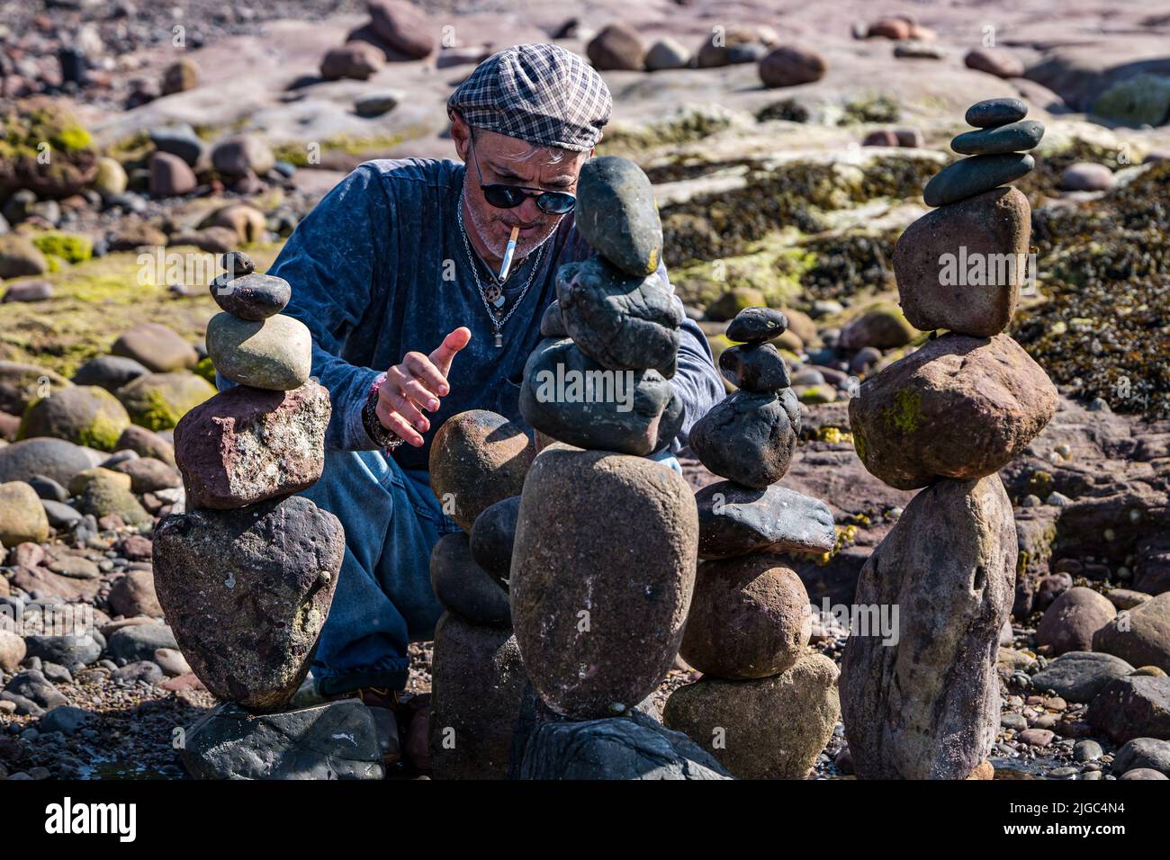 Dunbar, East Lothian, Scotland, UK, 9th July 2022. European Stone Stacking Championship: participants from all over the world have 3.5 hours to create an artistic artwork from the rocks on Eye Cave Beach. Pictured: Charlie Jordan from Texas. Credit: Sally Anderson/Alamy Live News Stock Photo