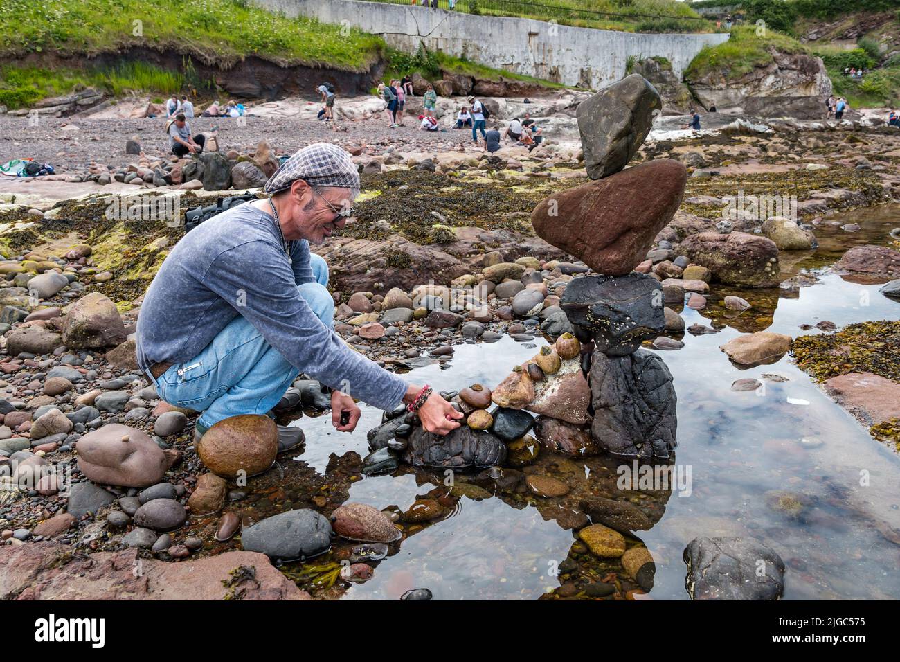 Dunbar, East Lothian, Scotland, UK, 9th July 2022. European Stone Stacking Championship: participants have 3.5 hours to create an artistic artwork from the rocks on Eye Cave Beach. Pictured: Charlie Jordan, stone stacker Stock Photo