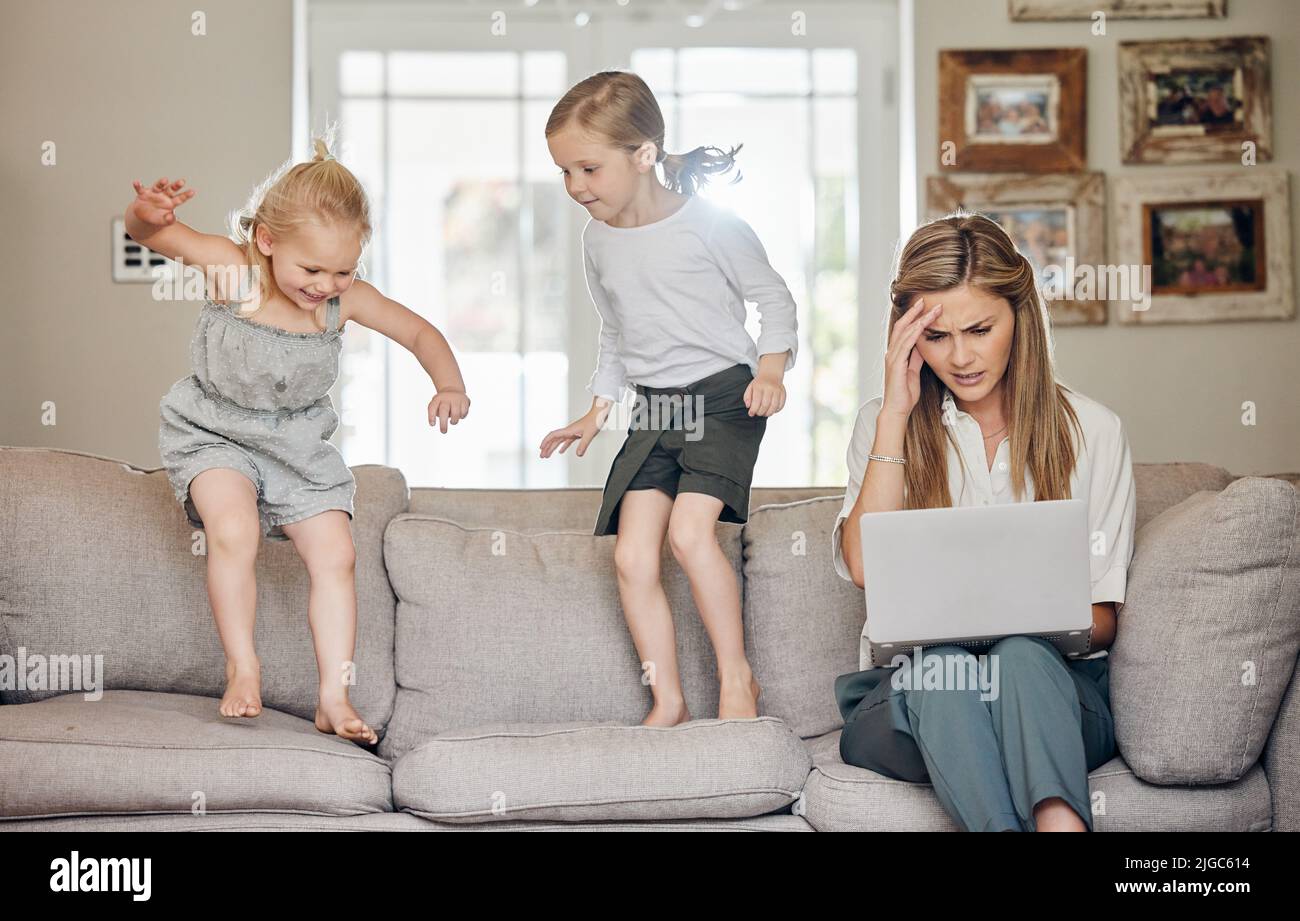 I wish life came with a pause button. a young woman looking stressed out while her children play around her at home. Stock Photo