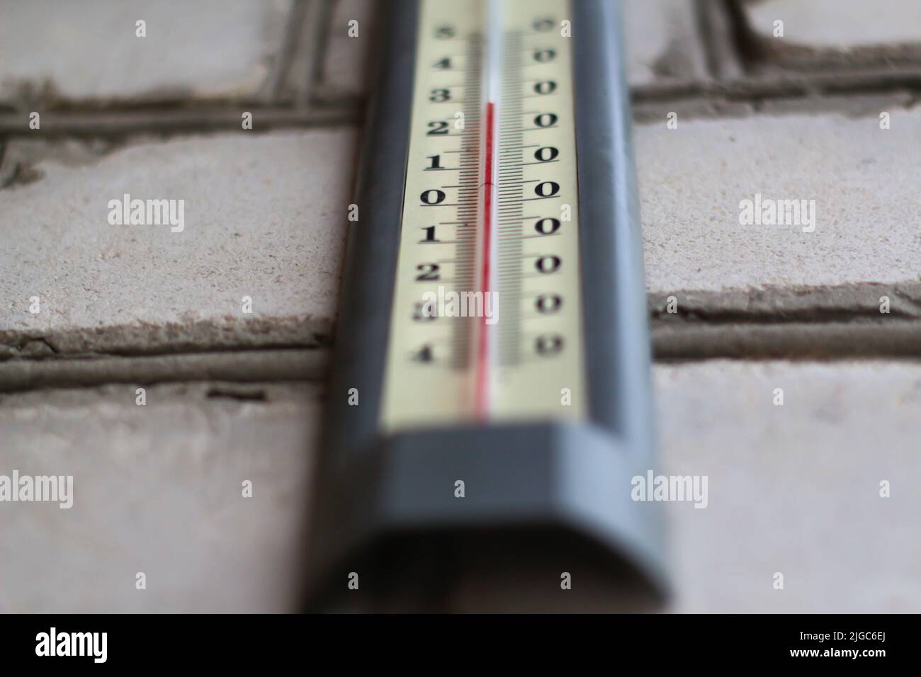 Defocus thermometer. Heat, thermometer shows the temperature is hot in the grey wall, Summer. Hot summer or heat wave background, glowing sun with the Stock Photo