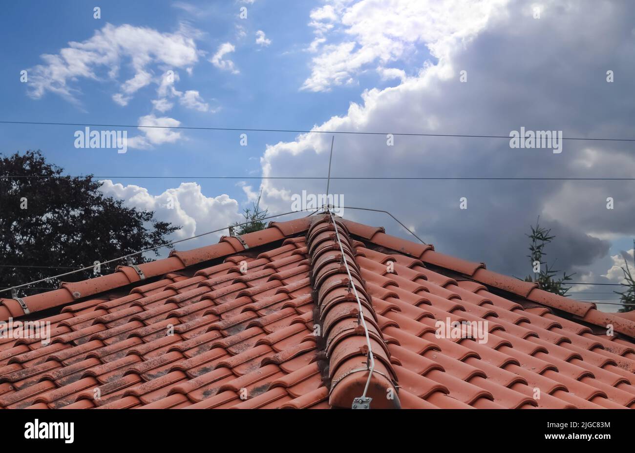 A roof with red shingles and a lightning conductor on it Stock Photo