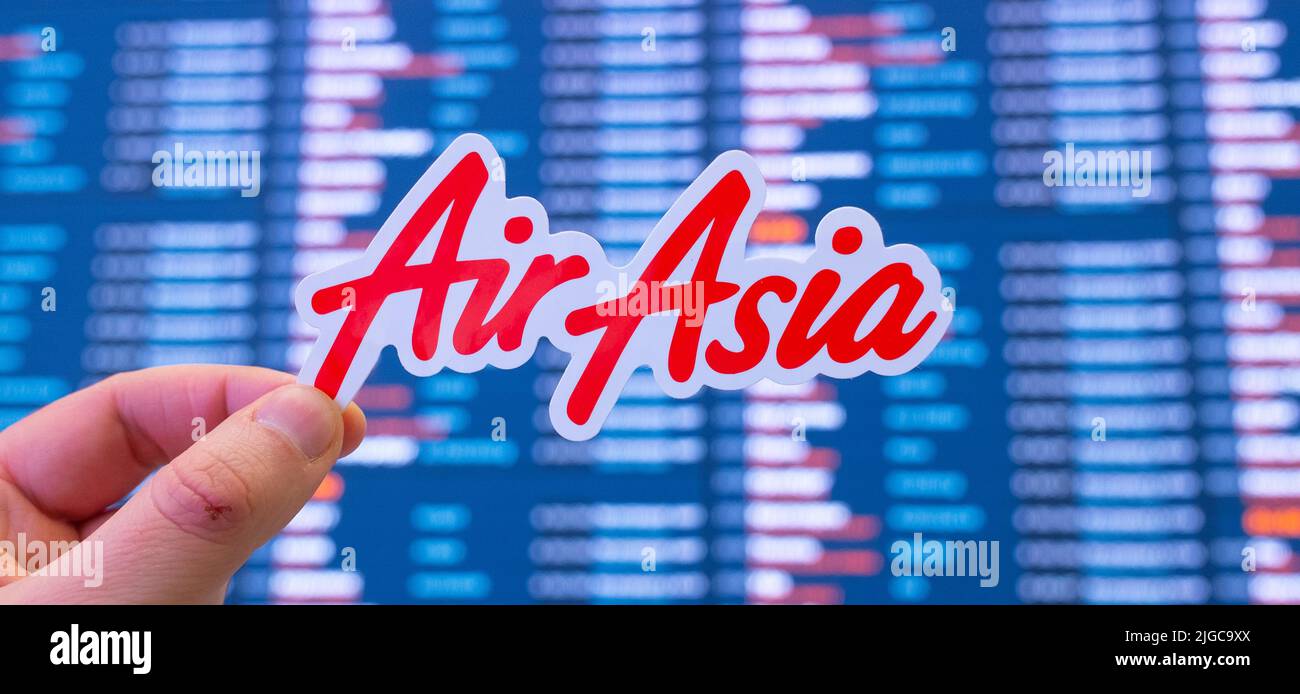 December 11, 2021, Kuala Lumpur, Malaysia. The emblem of AirAsia airline against the background of an electronic scoreboard with flight schedules at t Stock Photo