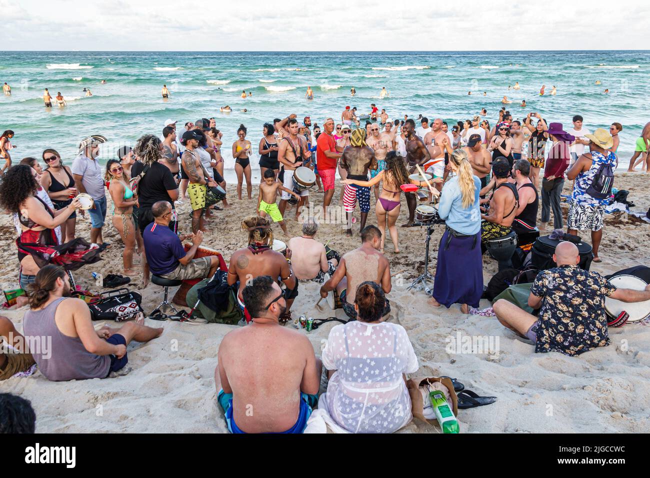 Miami Beach Florida,North Beach people sunbathers Hispanic men women families,Atlantic Ocean public beach drum circle dancers dancing people watching Stock Photo