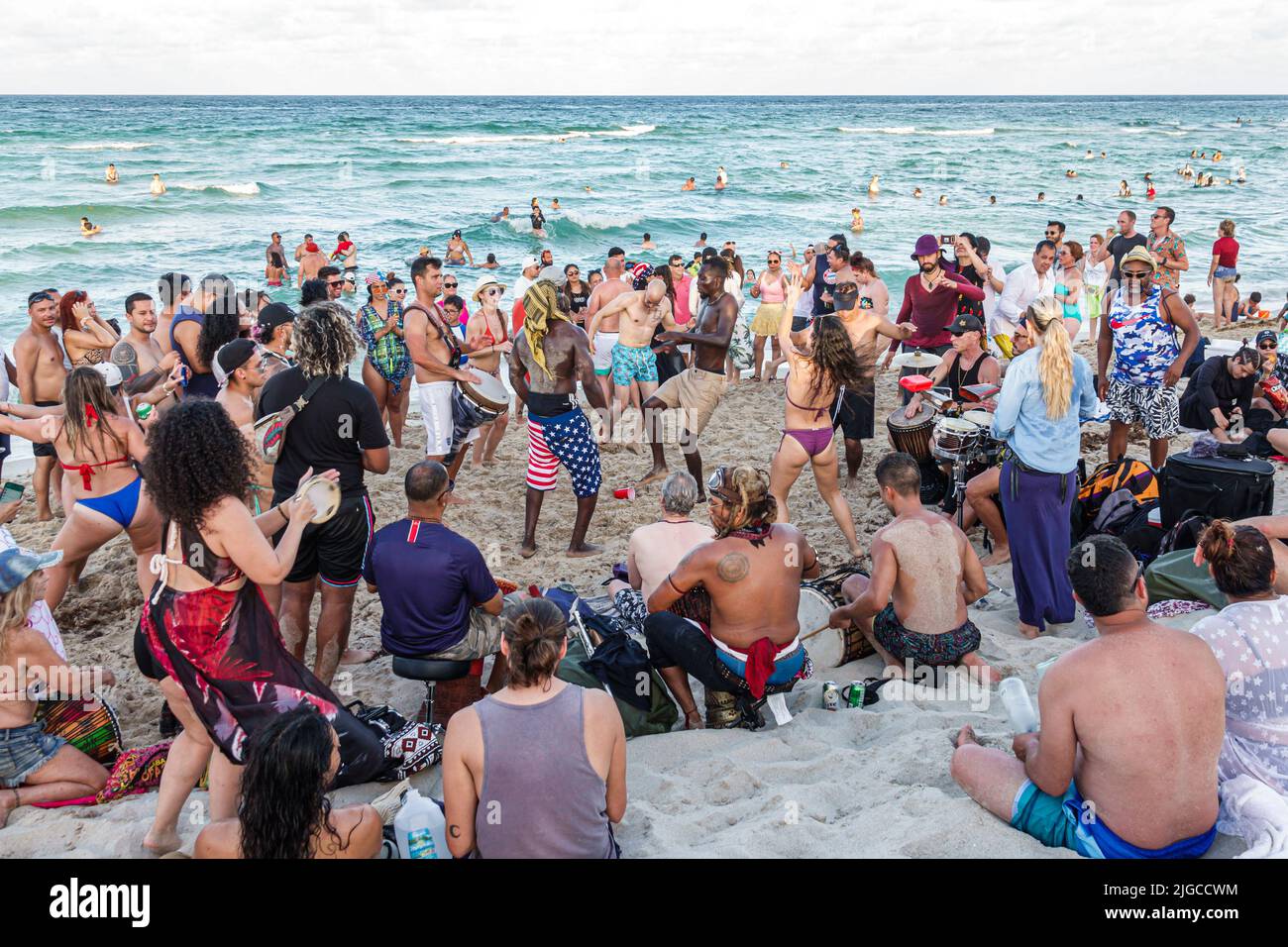 Miami Beach Florida,North Beach people sunbathers Hispanic men women families,Atlantic Ocean public beach drum circle dancers dancing people watching Stock Photo