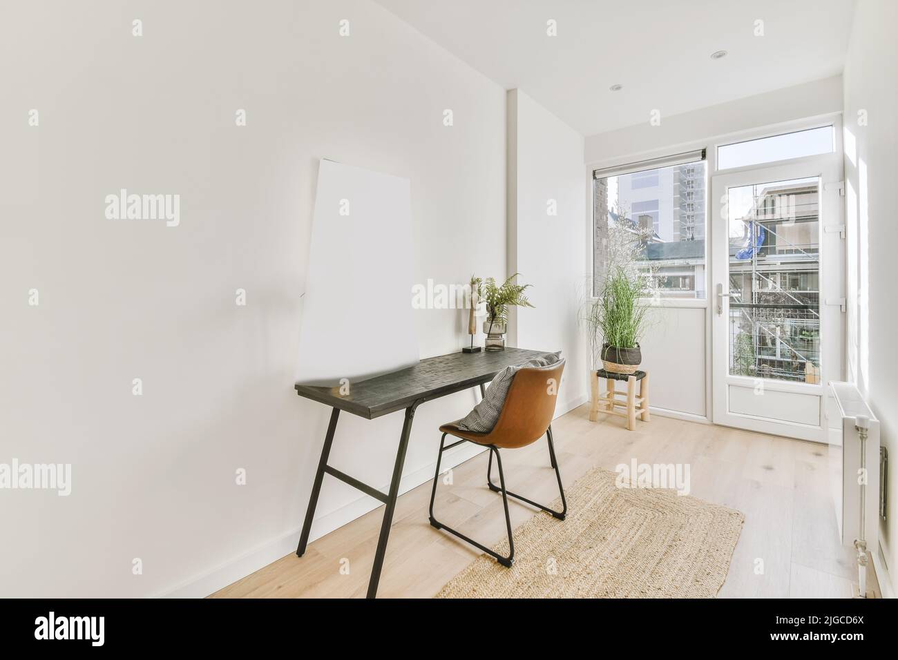 Narrow bright room with a balcony door, a table and a chair against a