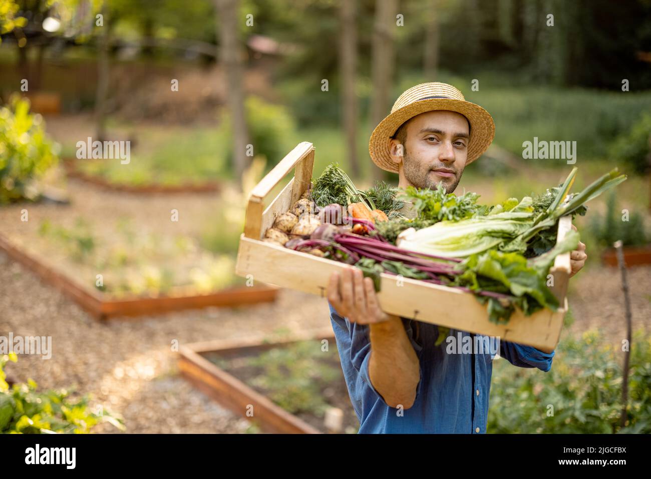 Farmer with freshly picked vegetables at farmland Stock Photo