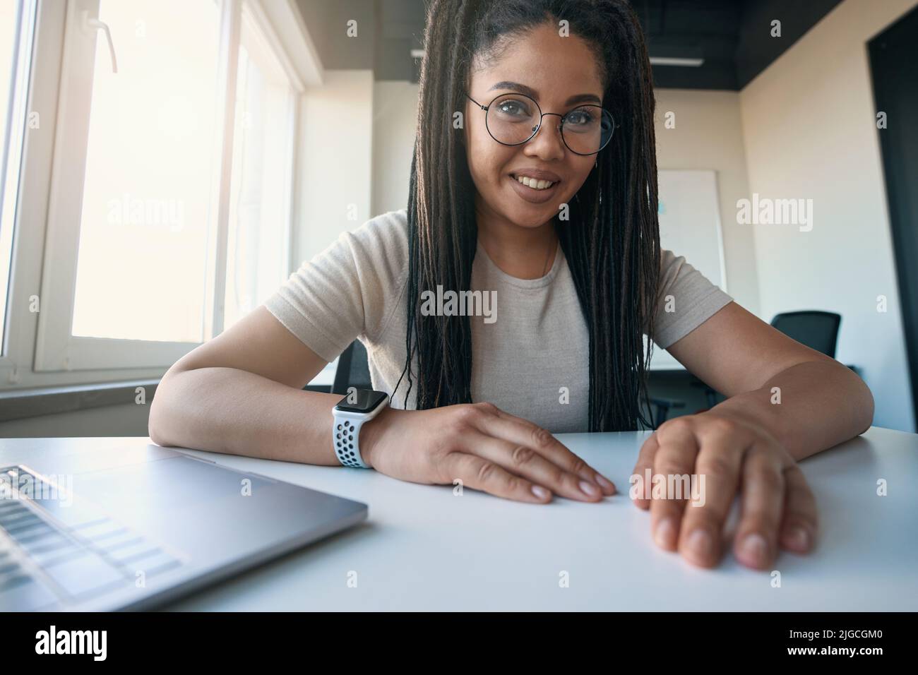 Joyous female office worker posing for camera at desk Stock Photo