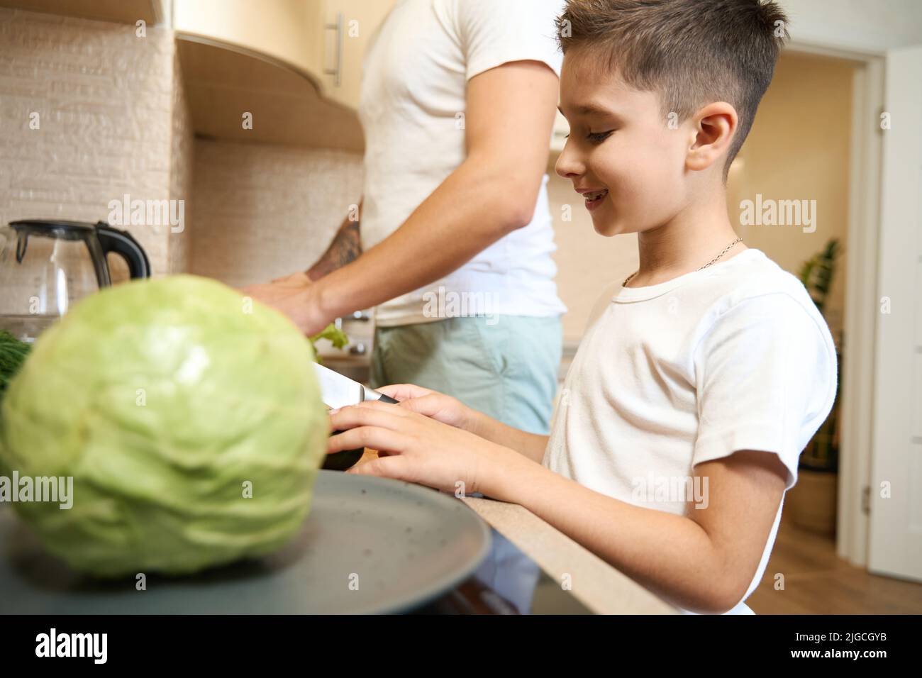 Son helping his parent in the kitchen with cooking Stock Photo - Alamy