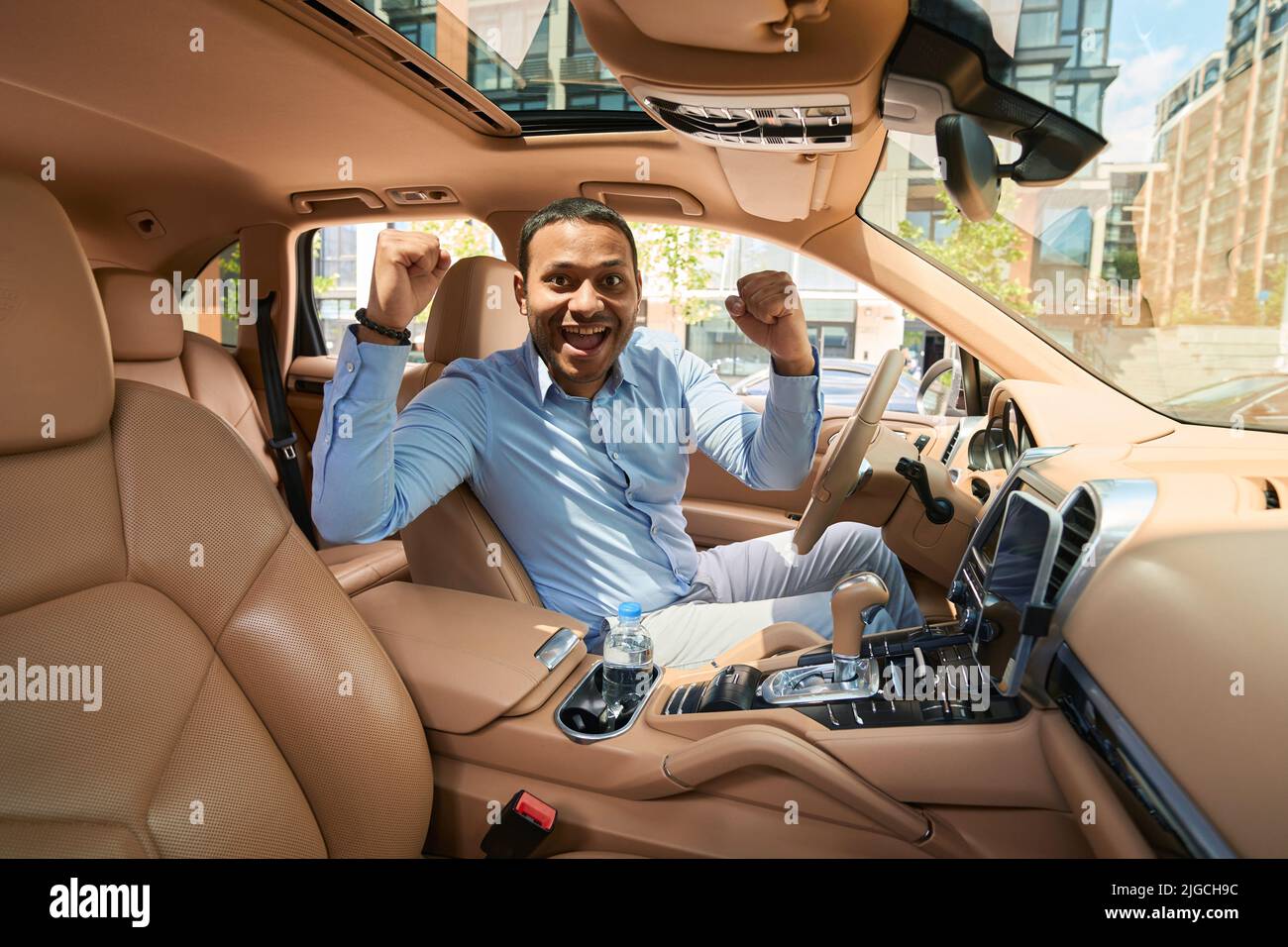 Happy motorist sitting at steering wheel of his car Stock Photo
