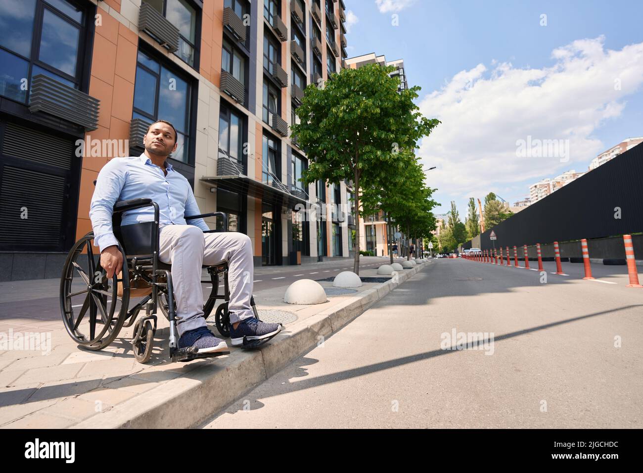 Serious wheelchairbound person attempting to cross street Stock Photo