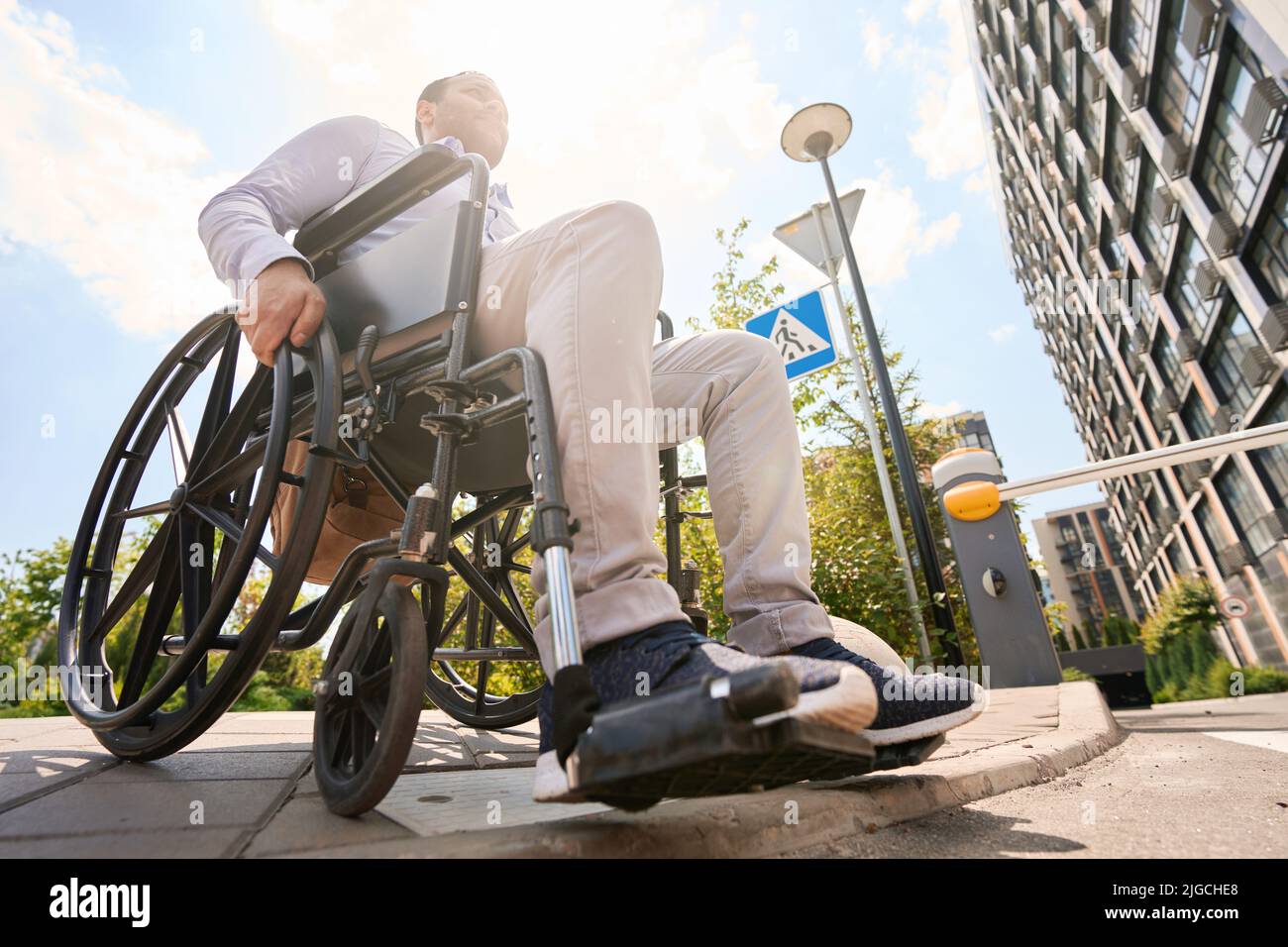 Wheelchairbound young man is descending sidewalk curb Stock Photo Alamy
