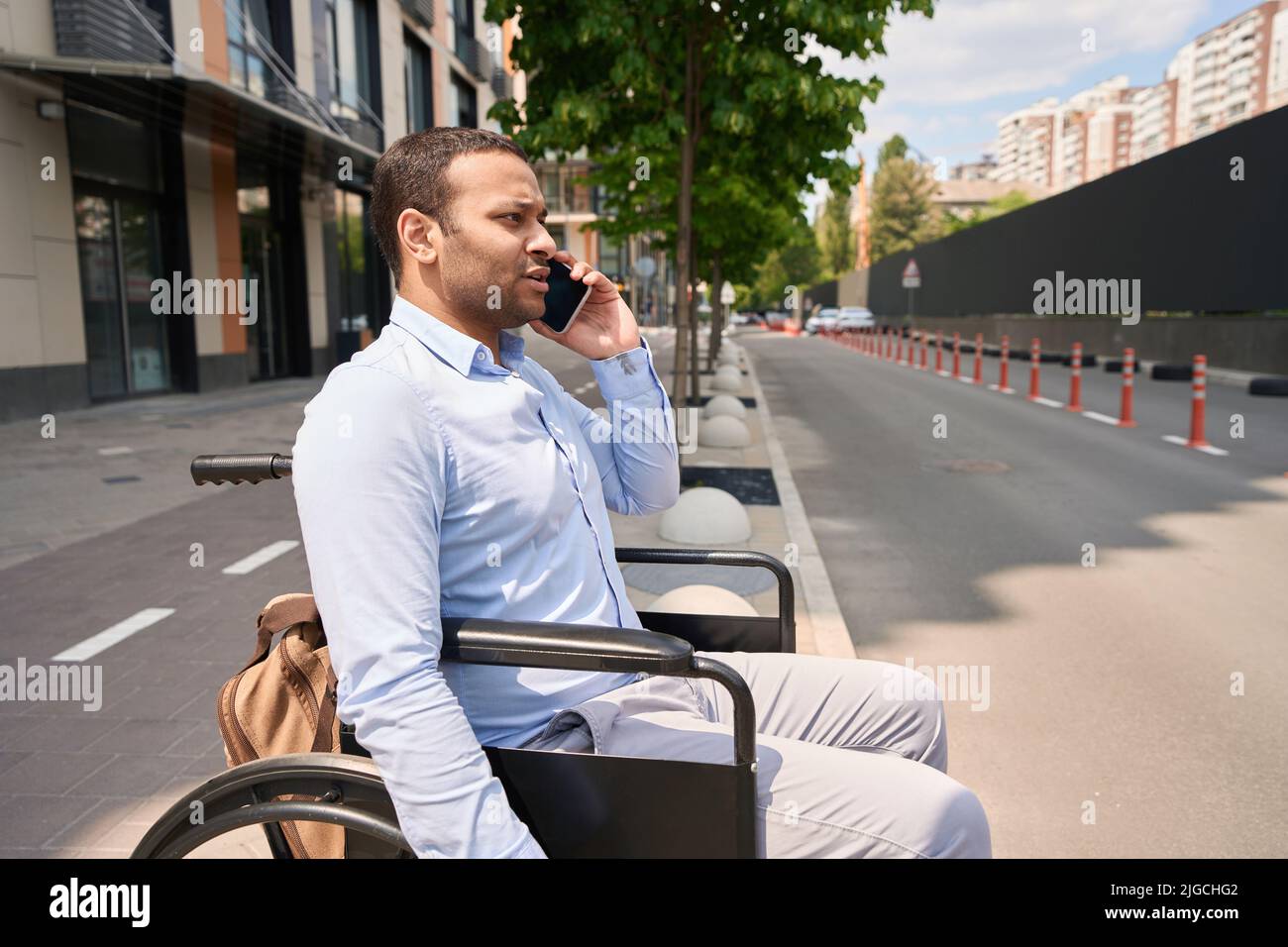 Serious wheelchairbound man talking on smartphone outdoors Stock Photo Alamy