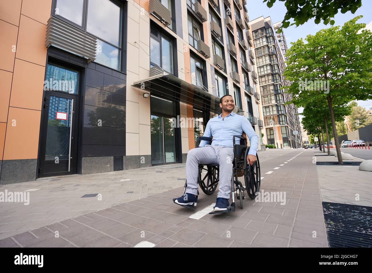 Young wheelchair-bound man looking around business district Stock Photo