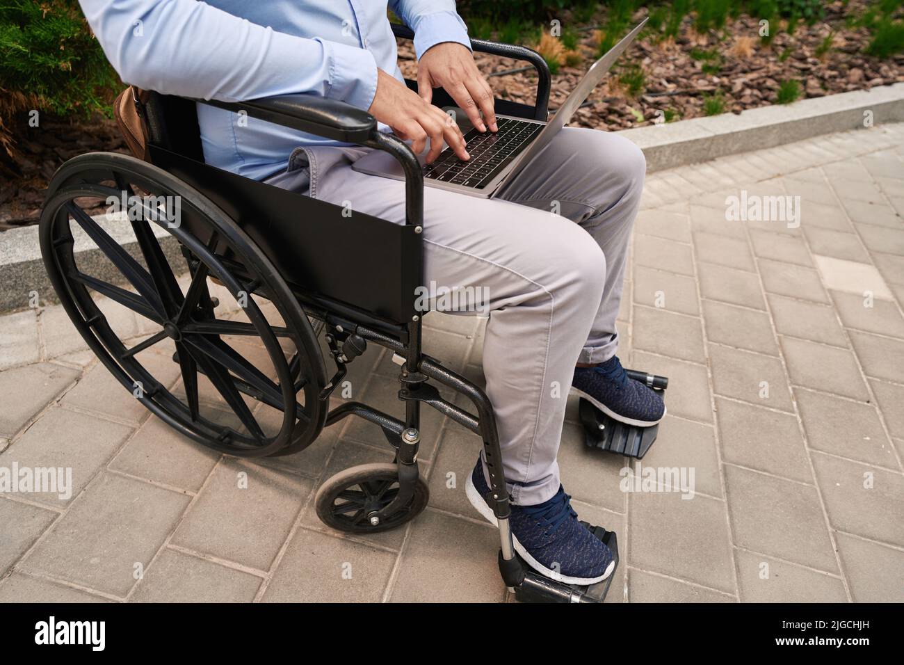 Person with disability typing on laptop outside Stock Photo