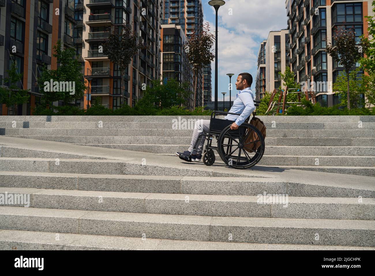 Wheelchair-bound man climbing stairs in business district Stock Photo