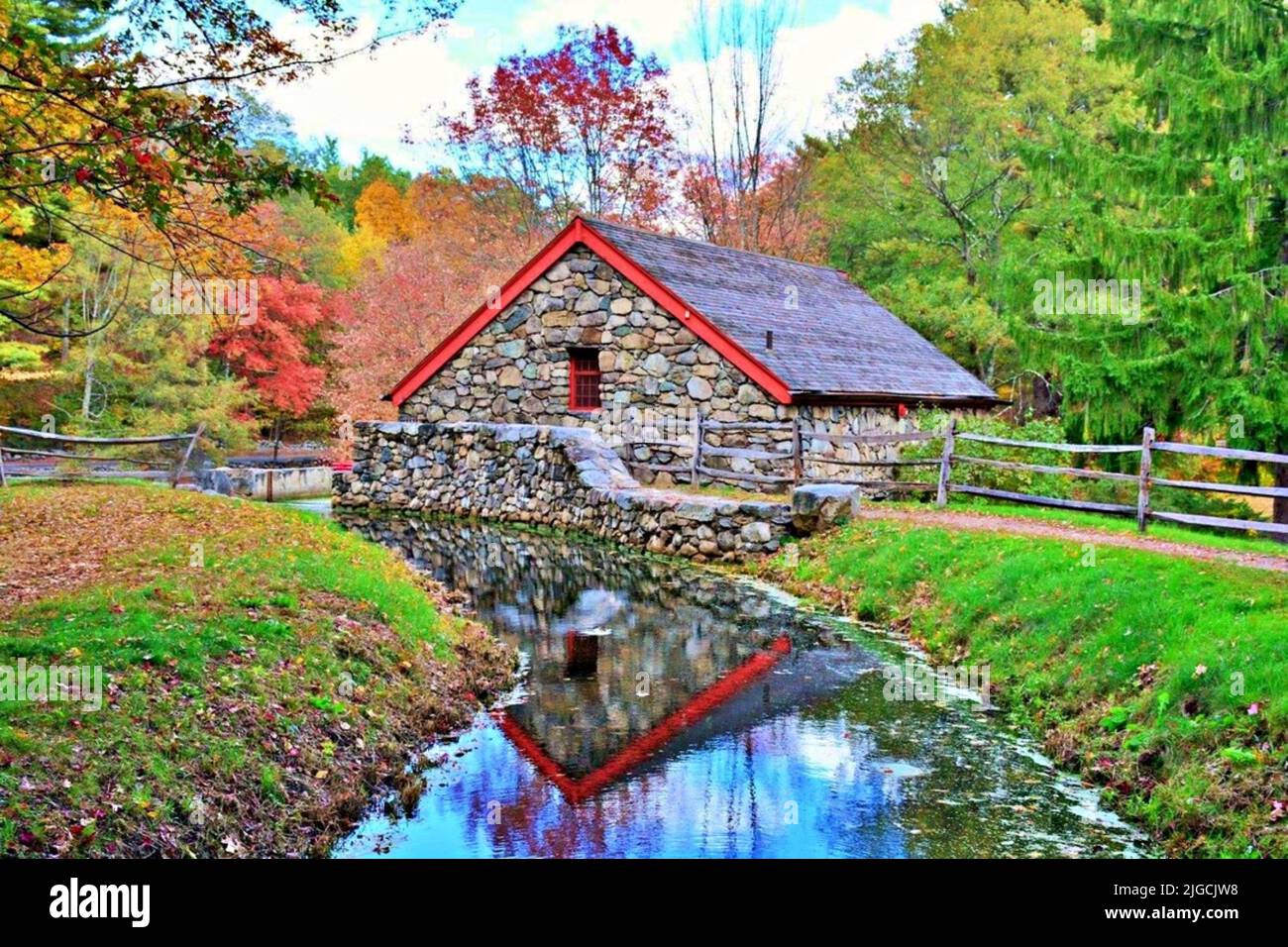 The backside of the Grist Mill located in Sudbury, Massachusetts reflecting in Grist Mill Pond Stock Photo